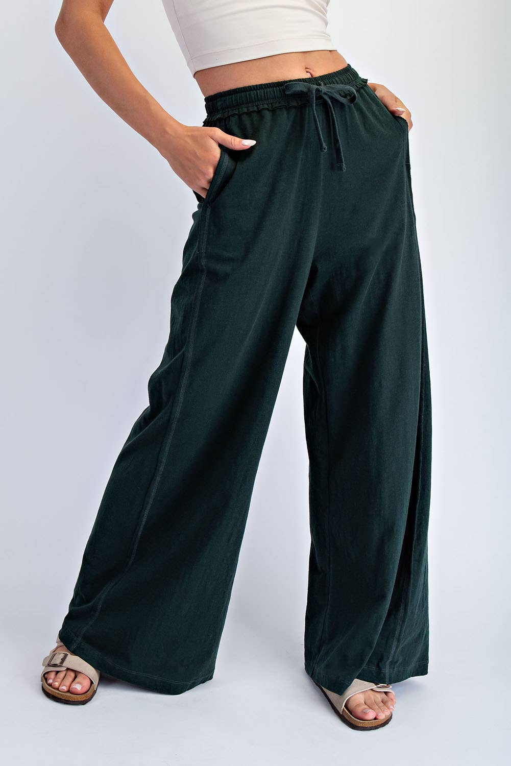 Person wearing dark green wide-leg pants on a white background