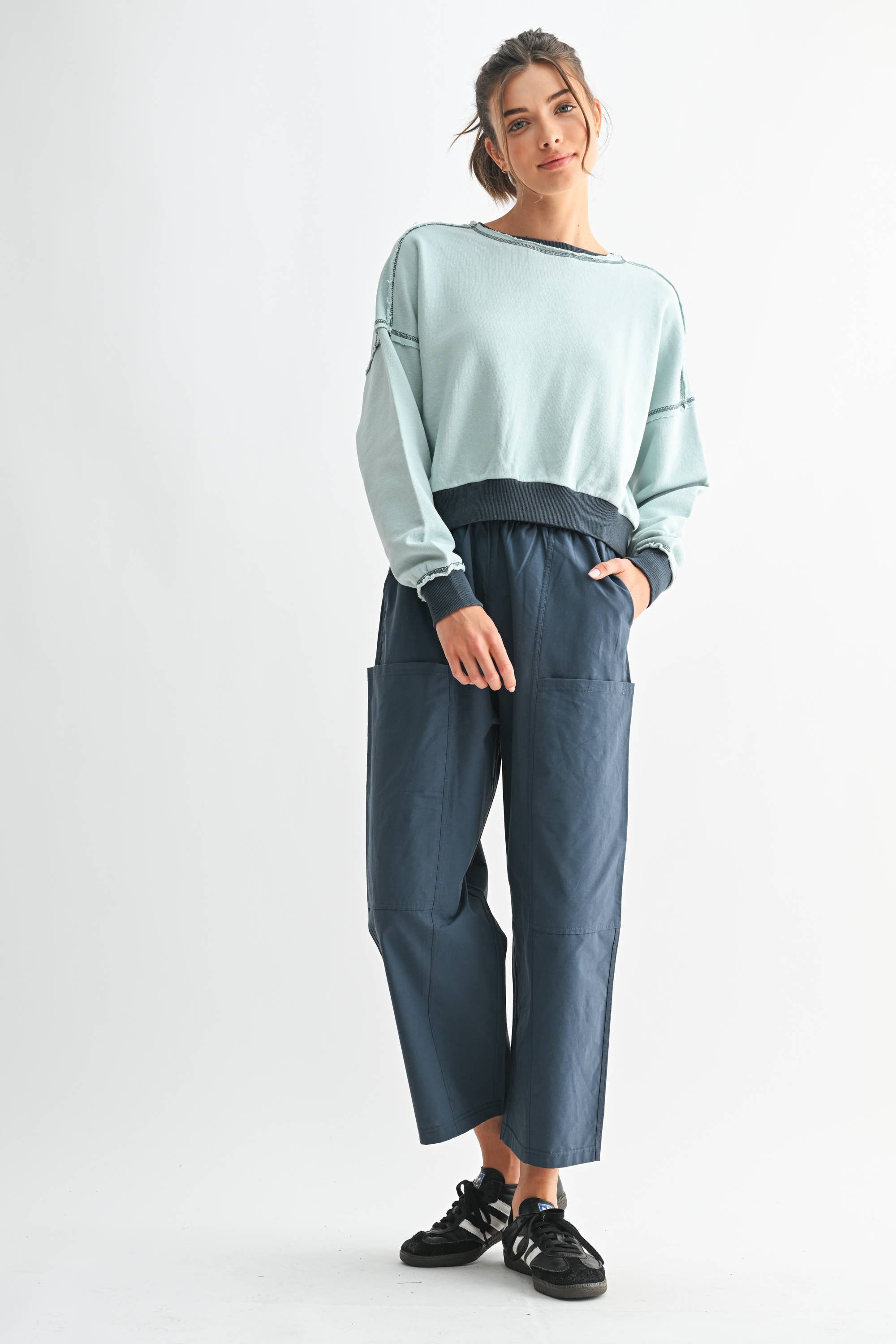 Woman wearing a light blue sweater and dark blue pants on a white background