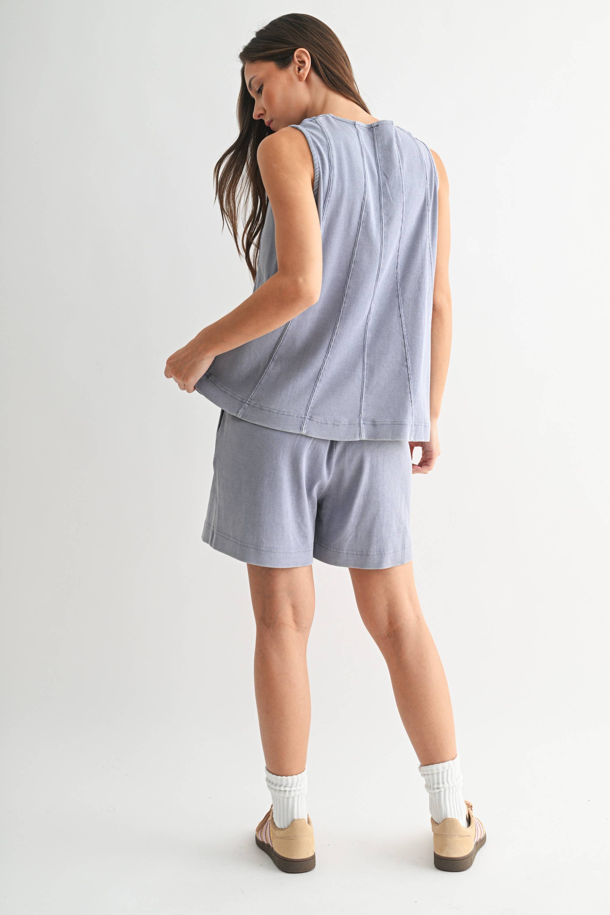 Woman wearing a light blue sleeveless top and shorts set on a white background