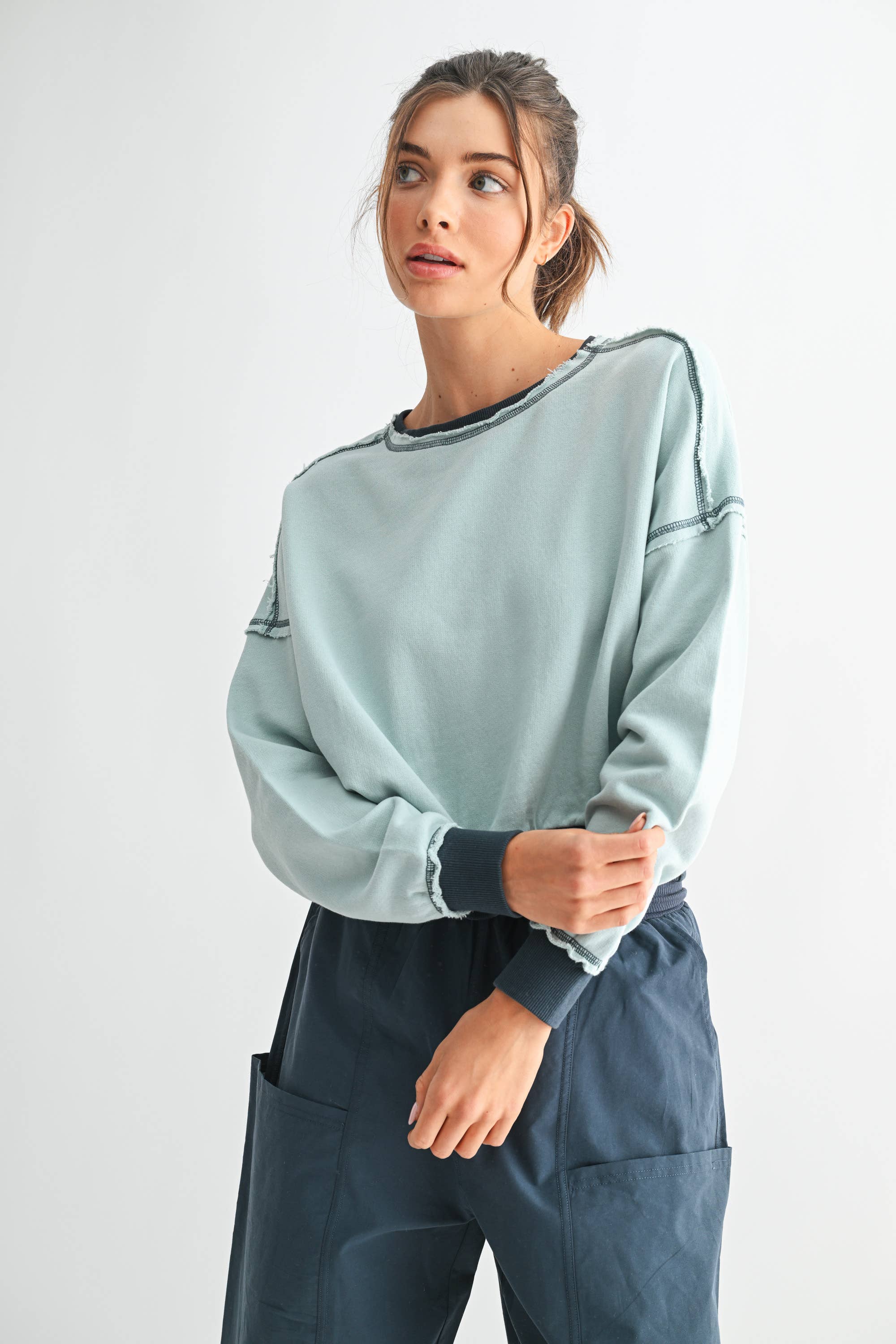 Woman wearing a light gray sweatshirt and dark blue pants on a white background