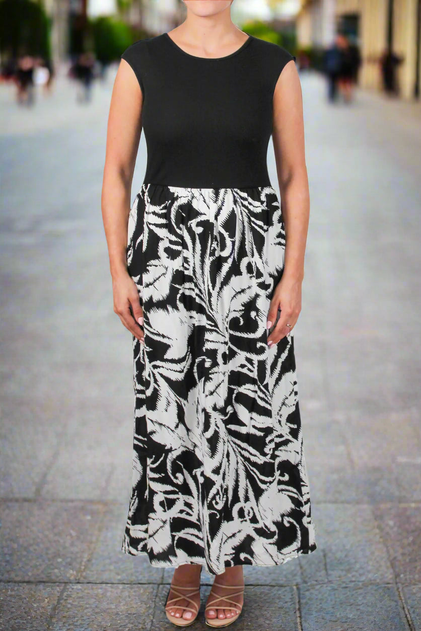 Woman wearing a black sleeveless top and a long black and white floral skirt on a white background