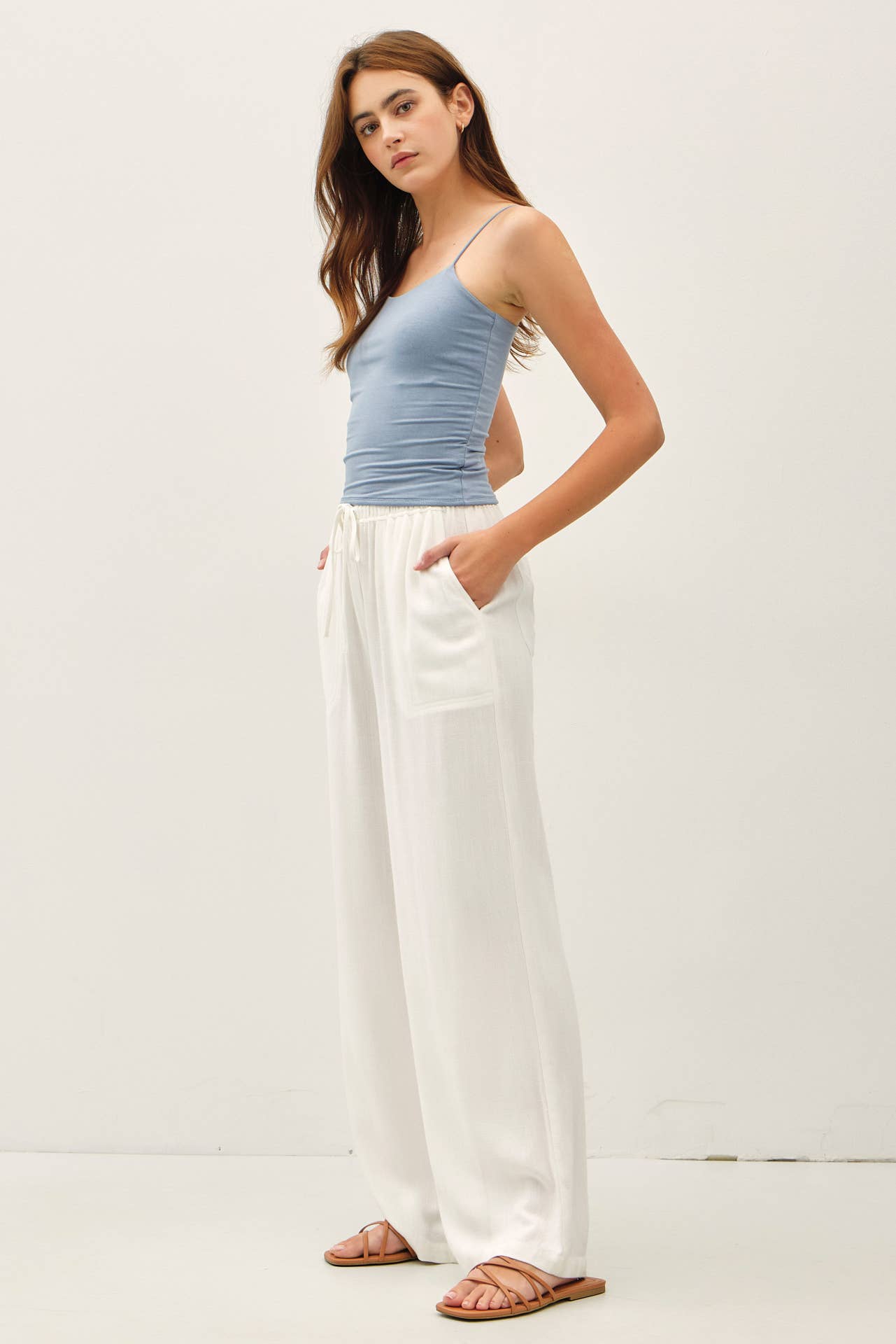 Woman wearing a light blue top and white pants on a white background