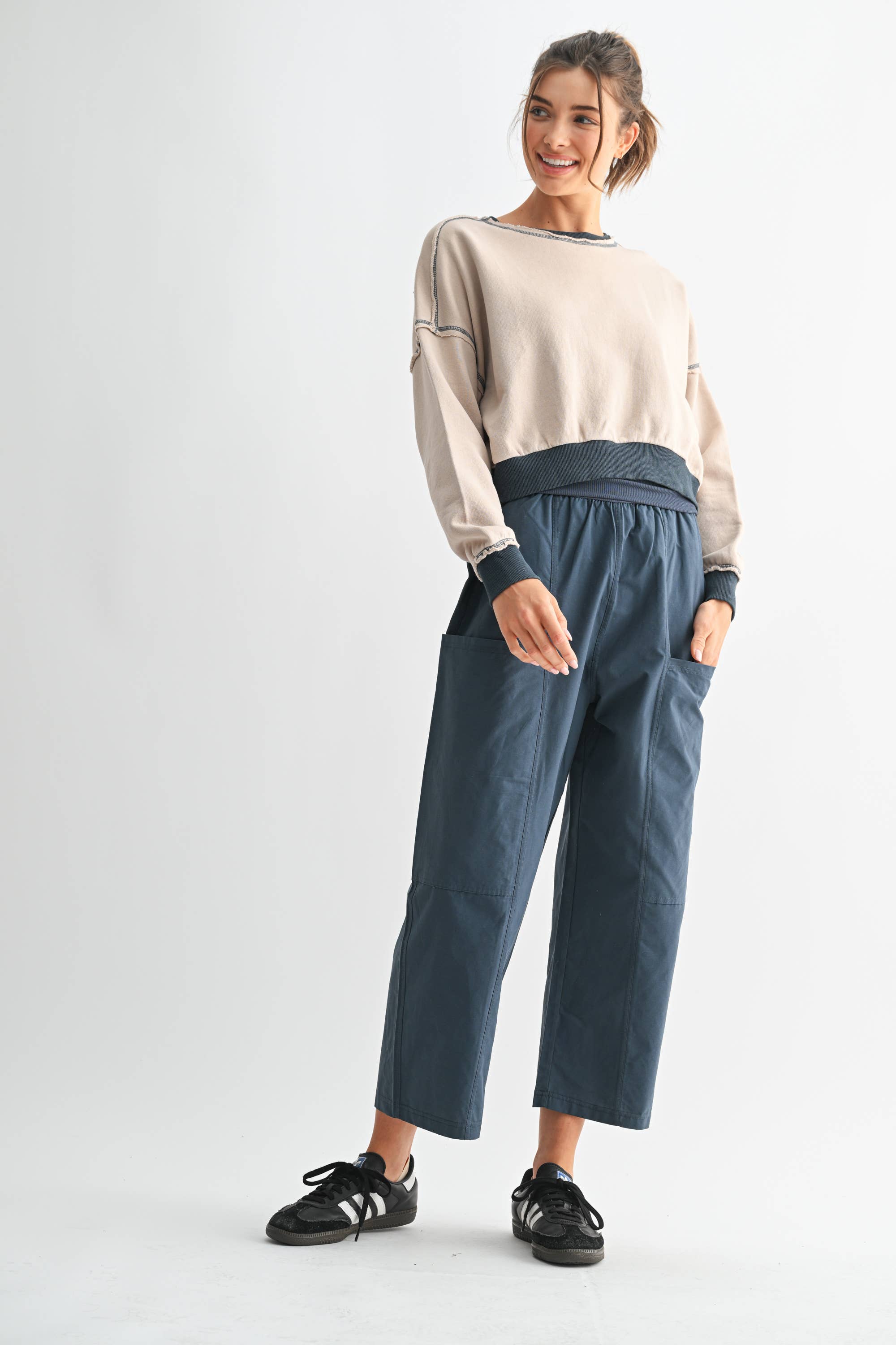 Woman wearing a beige sweater and blue pants on a white background