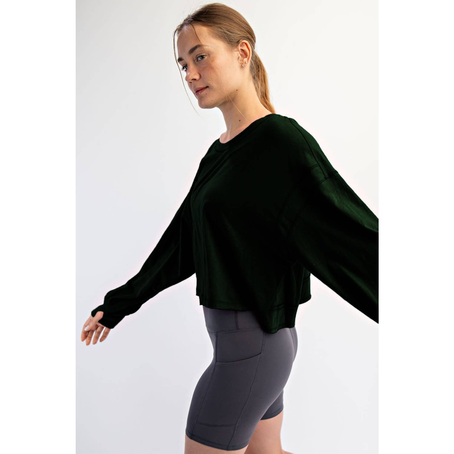 Woman wearing a dark green sweater and gray shorts on a white background