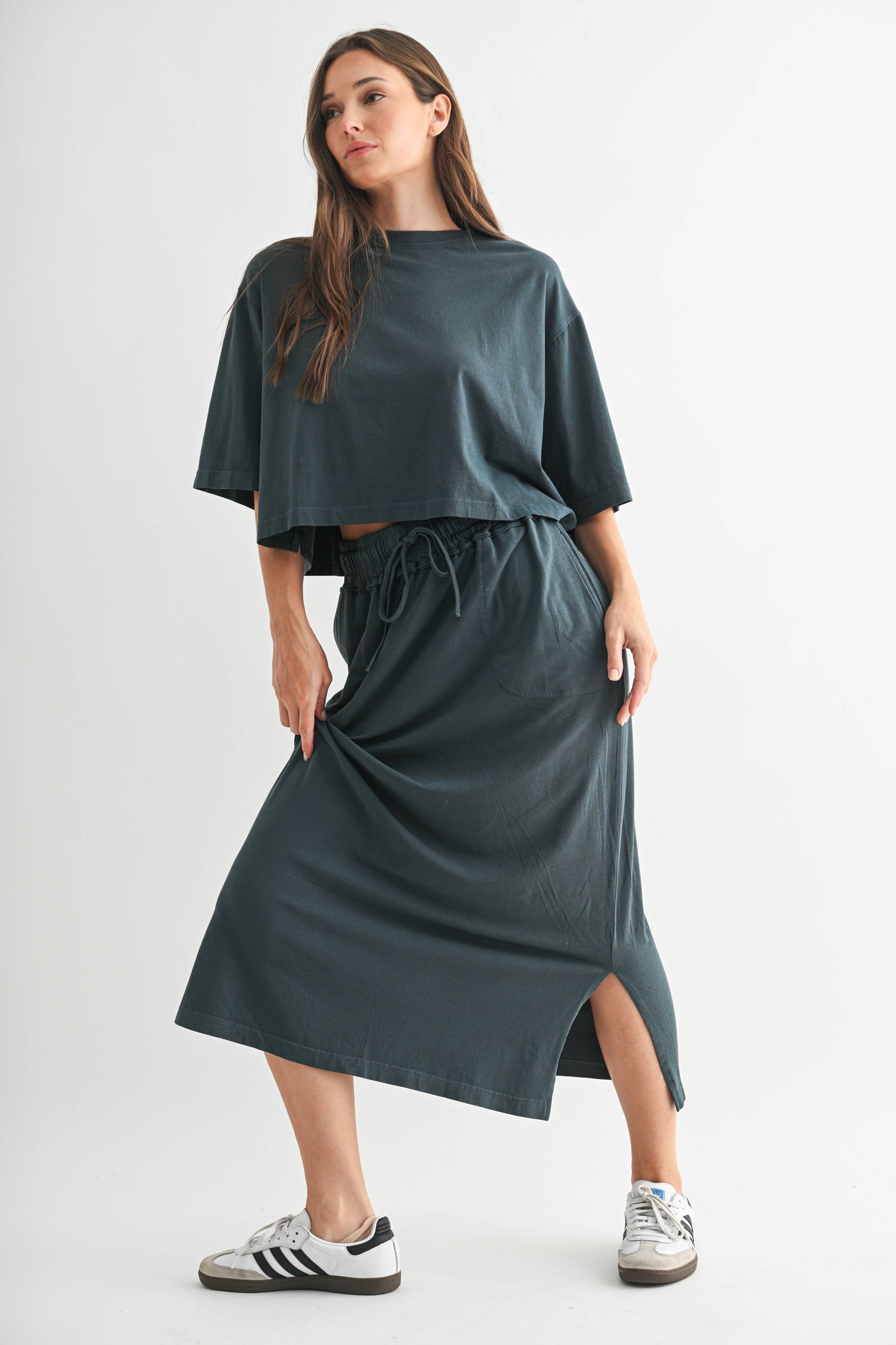 Woman wearing a teal outfit with a skirt and top on a white background