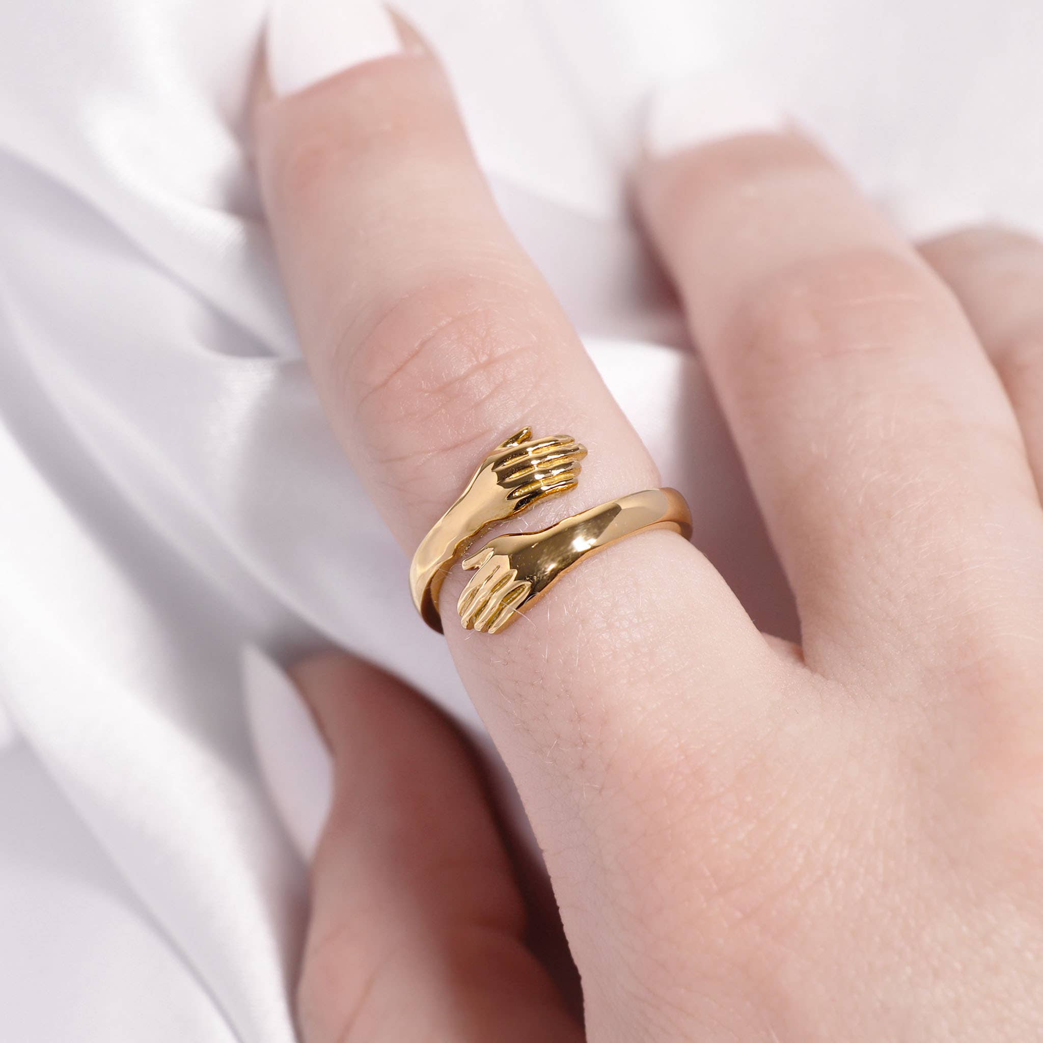 Gold ring with a unique design on a person's finger against a white background