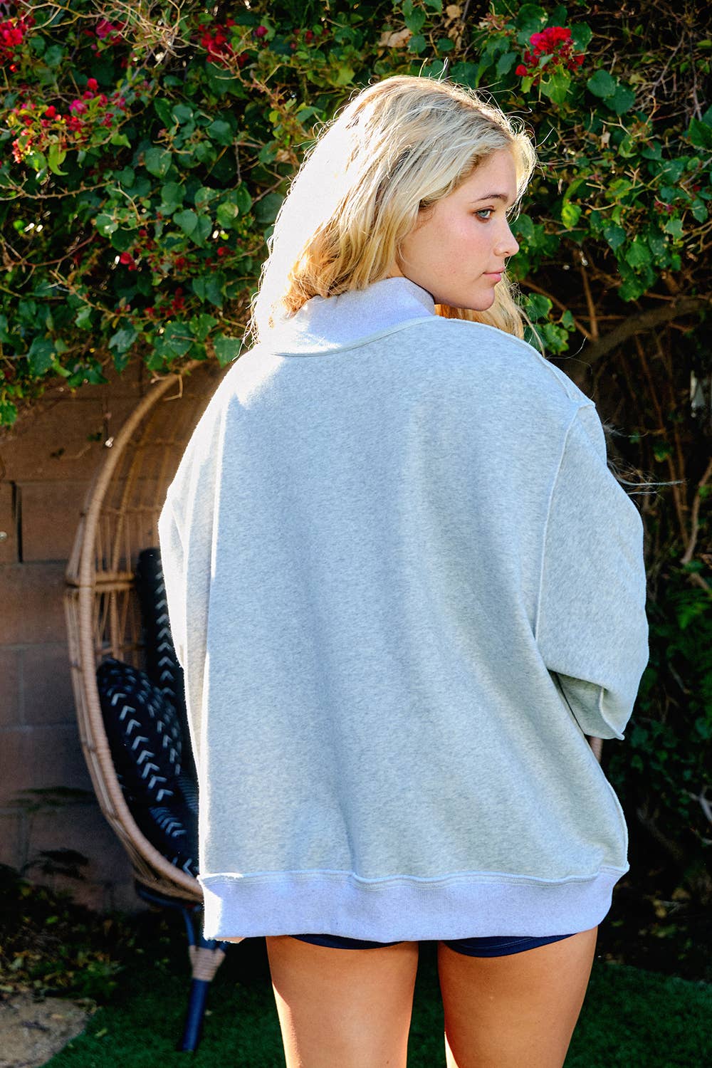 Woman wearing a light gray sweater with a floral background