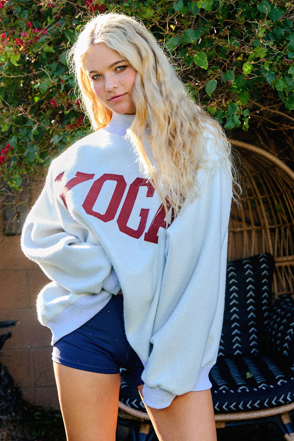 Person wearing a white sweatshirt with red text and blue shorts outdoors.