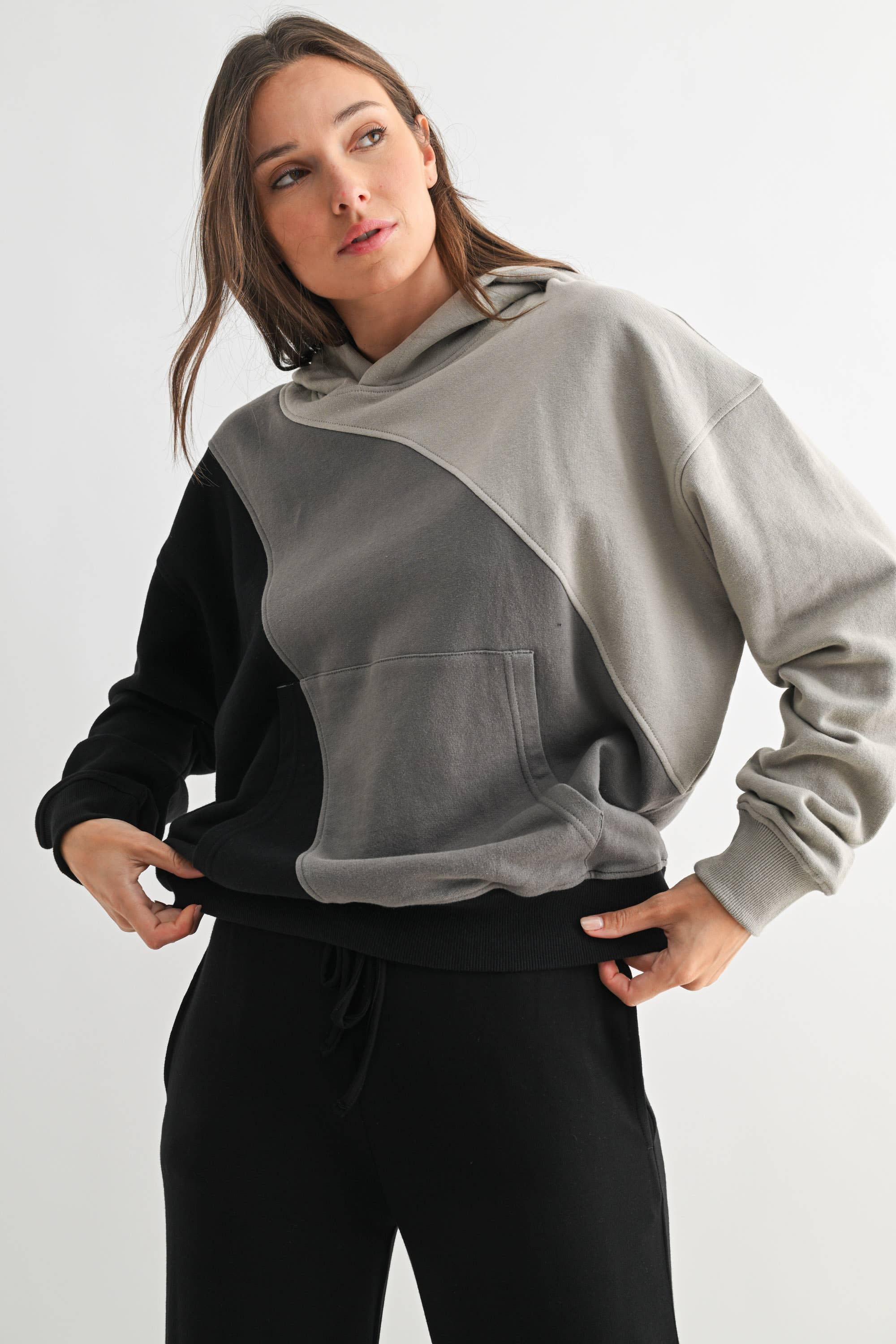 Woman wearing a gray and black color-blocked hoodie on a white background