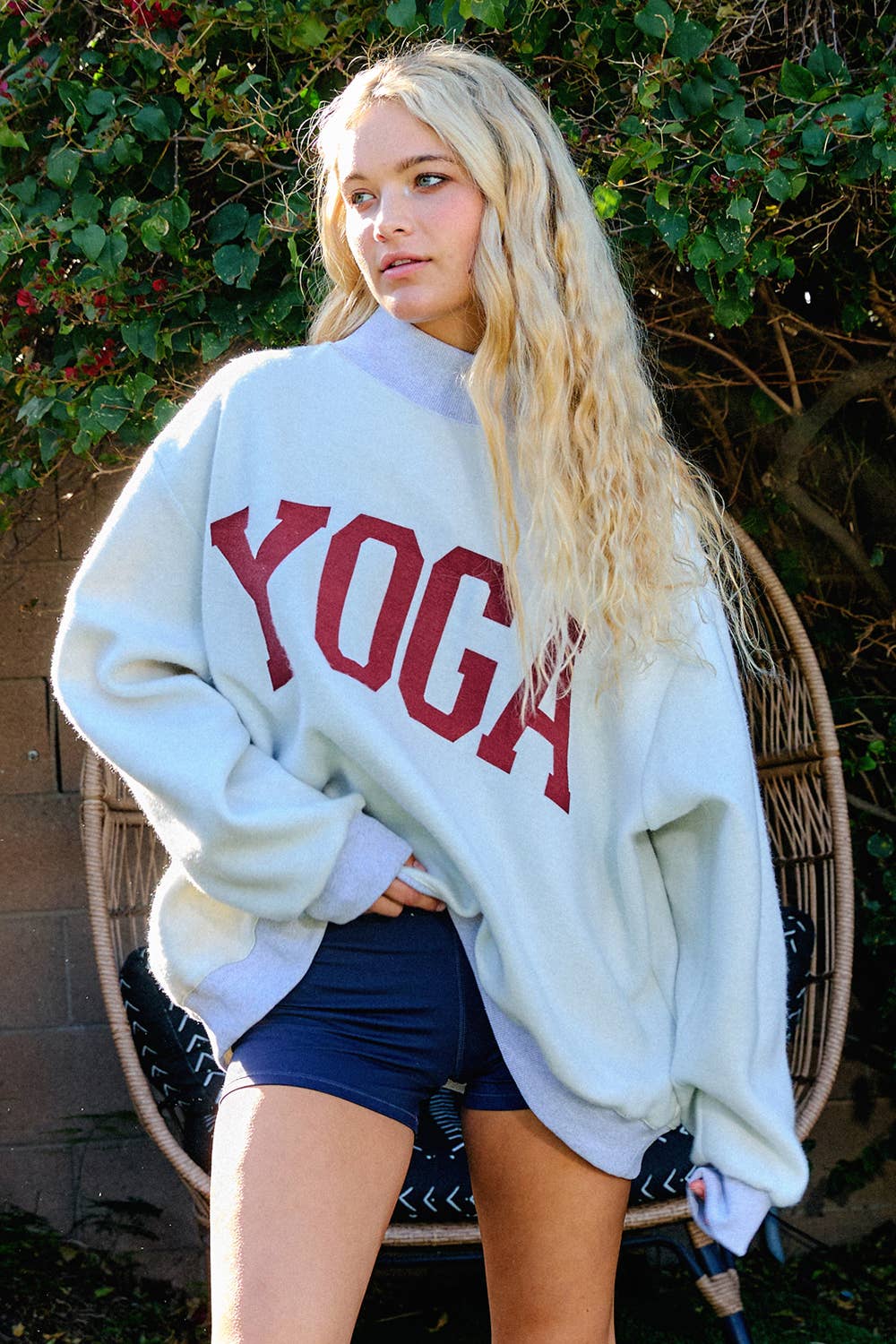 Person wearing a white sweatshirt with 'YOGA' printed in red, standing outdoors.