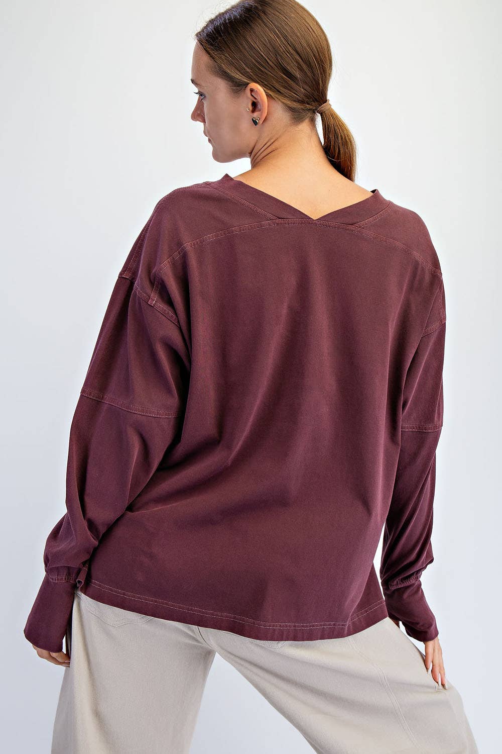 Person wearing a burgundy long-sleeve top on a white background