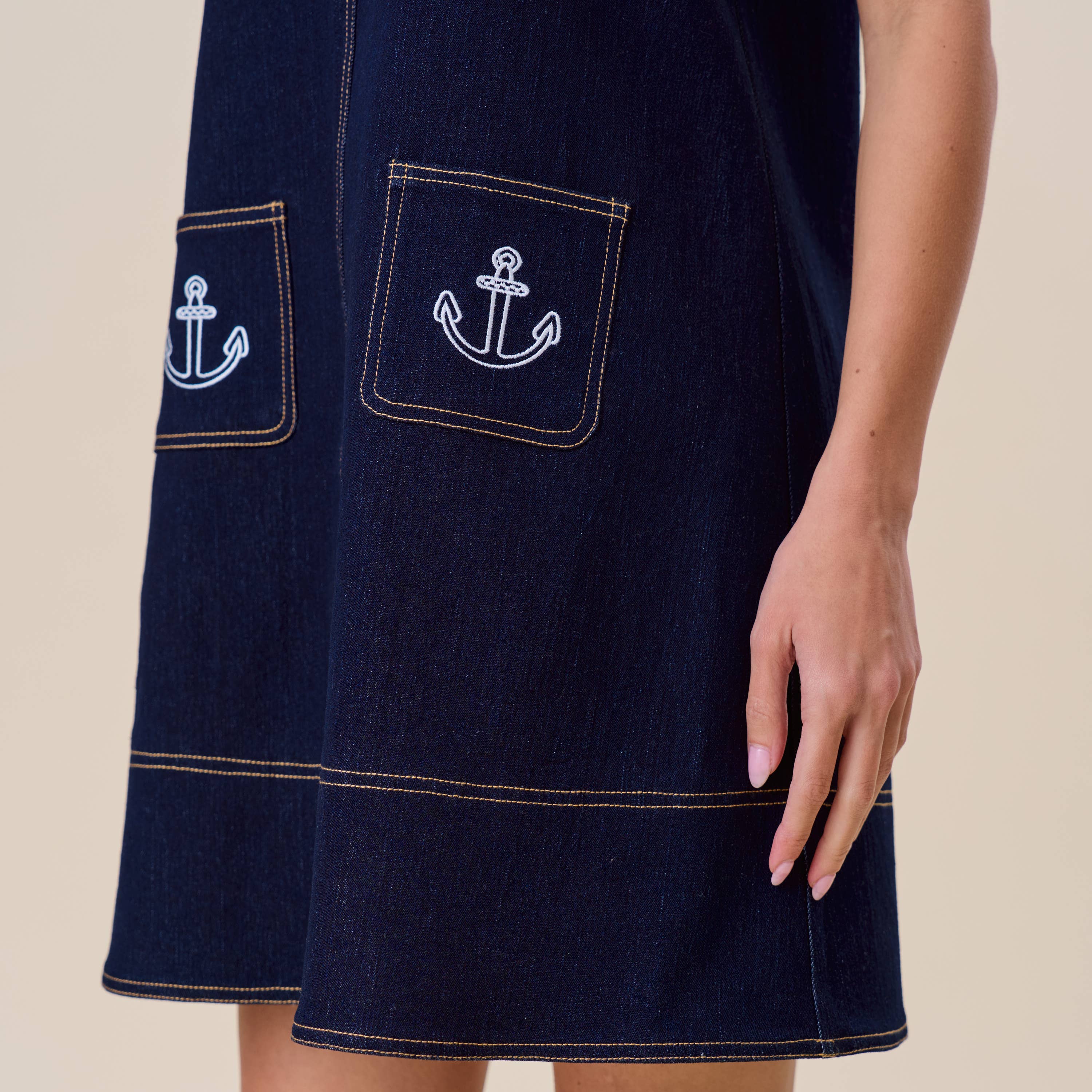 Navy dress with anchor pockets on a beige background