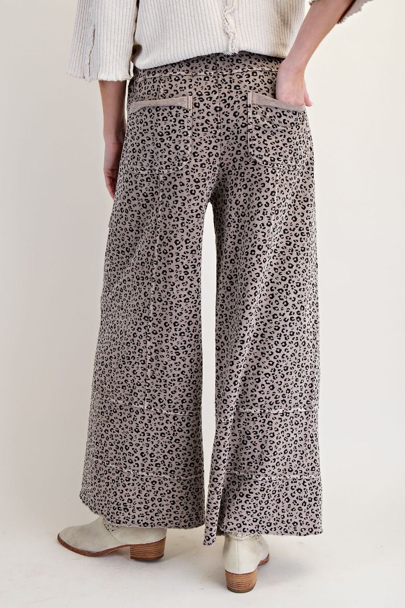 Person wearing leopard print wide-leg pants on a plain background