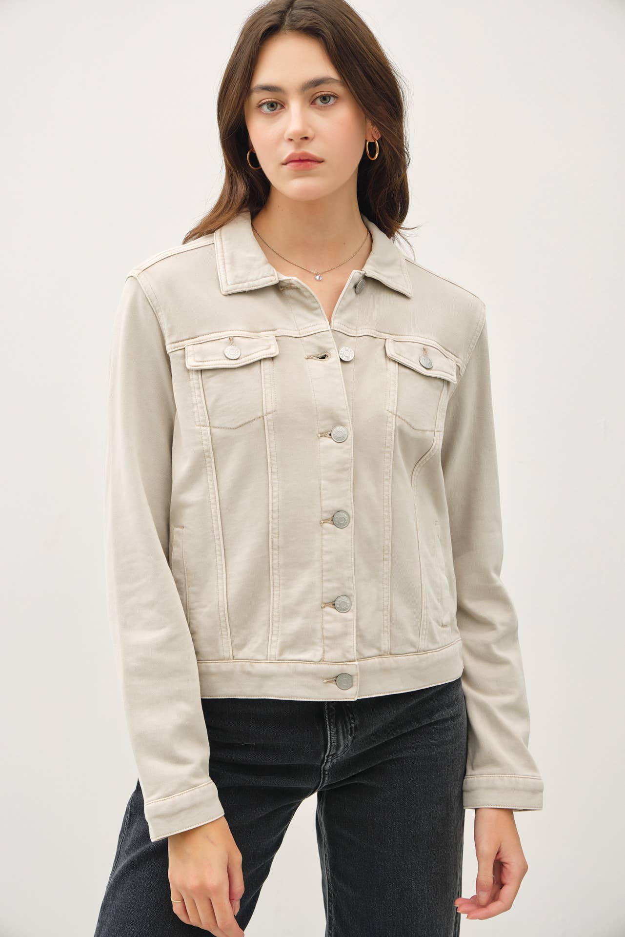 Woman wearing a beige denim jacket against a white background