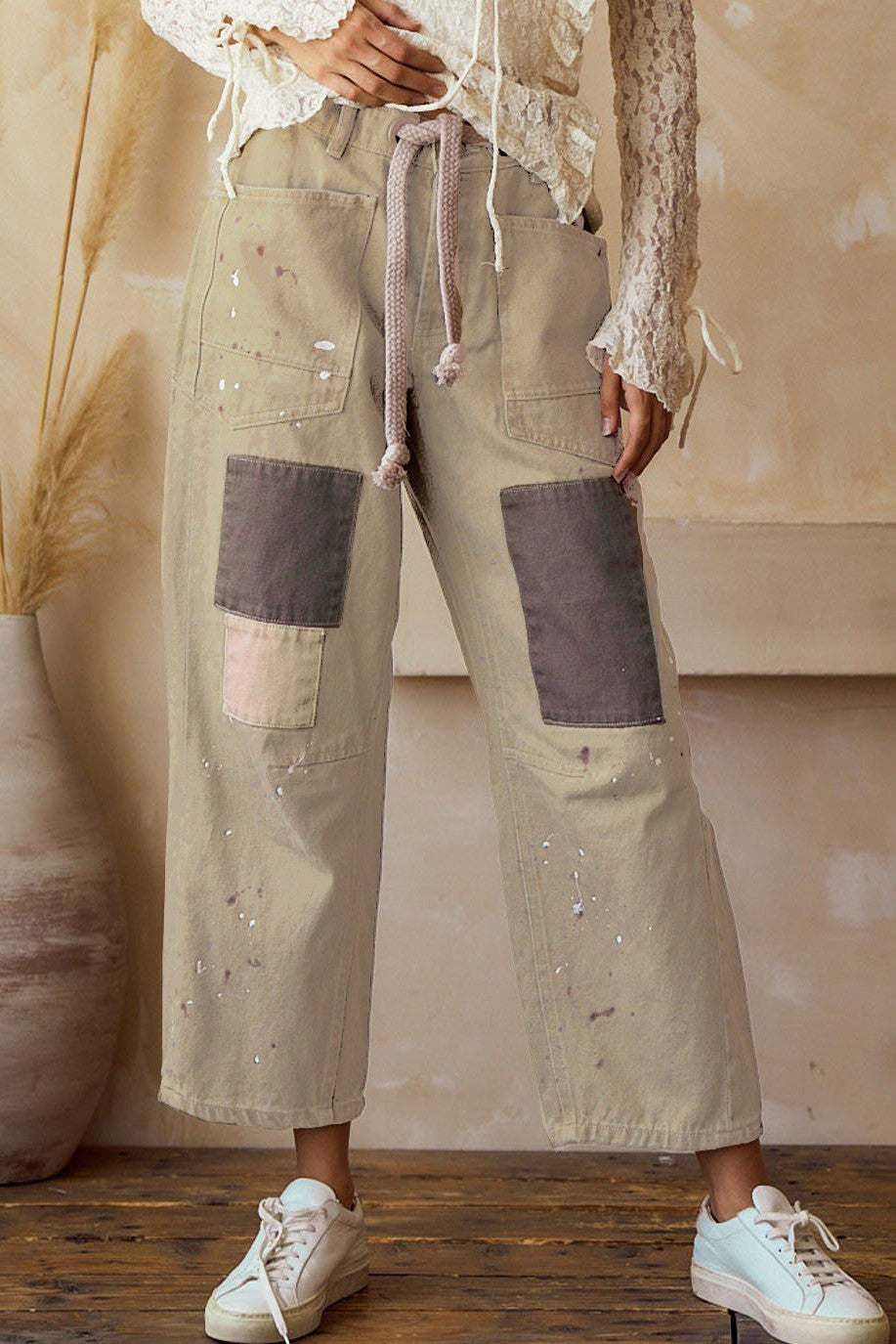 Person wearing beige patchwork pants with a neutral background