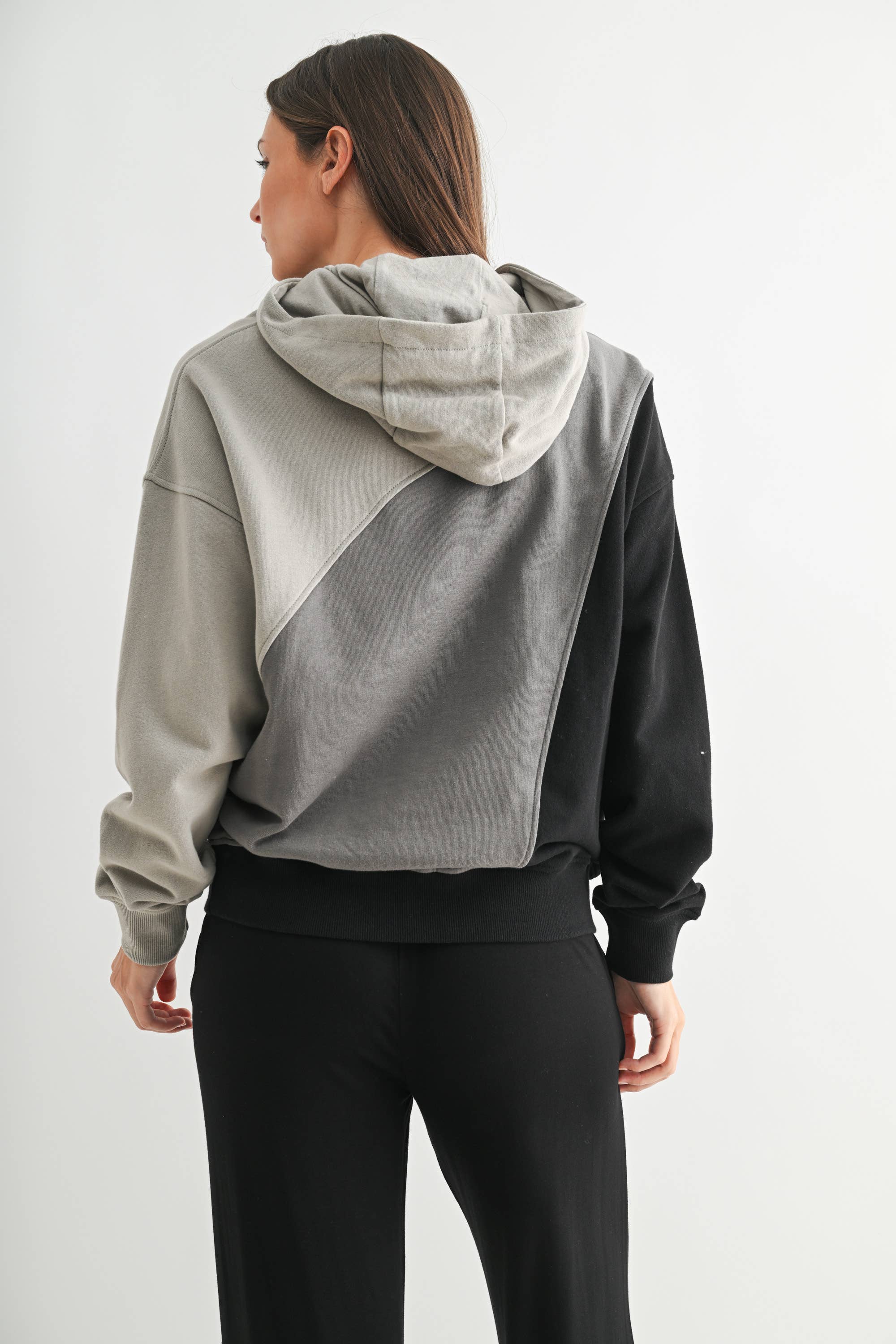 Person wearing a gray and black color-blocked hoodie on a white background