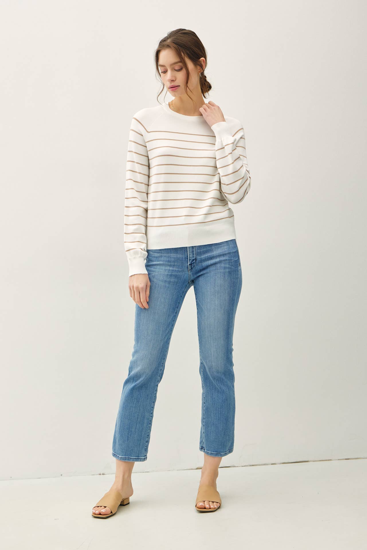 Woman wearing a striped sweater and blue jeans on a white background
