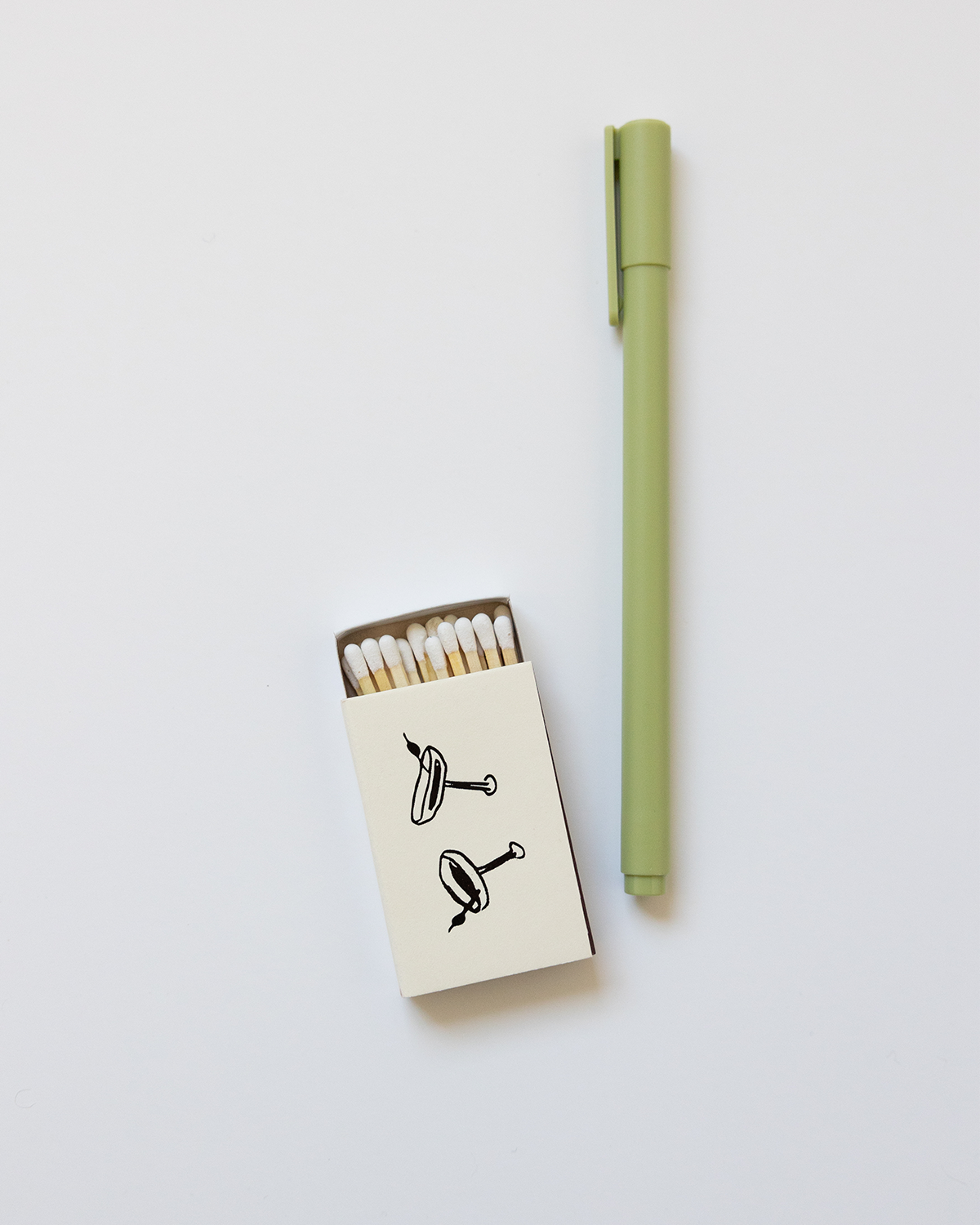 Green pen and matchbox with matches on a light gray background