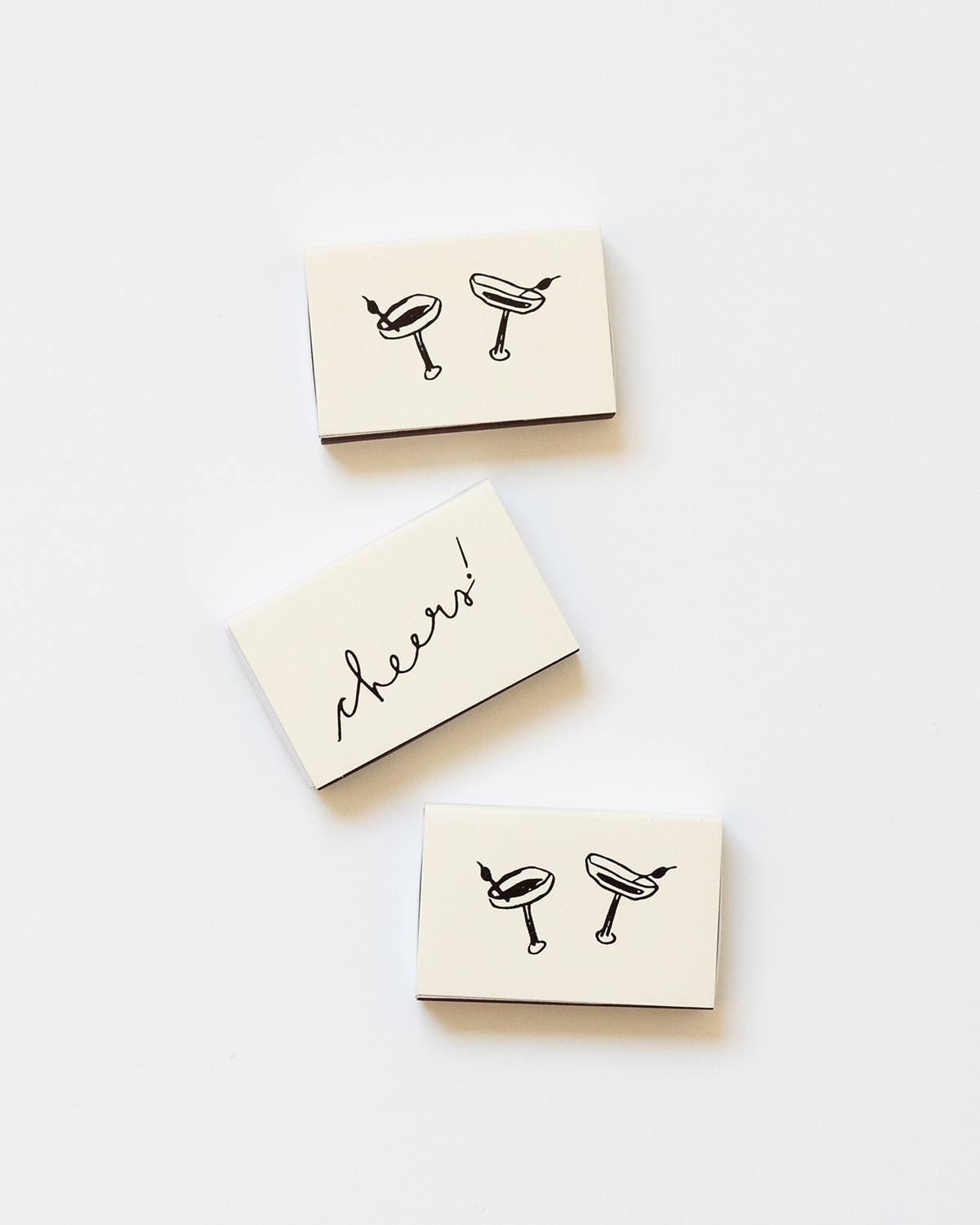 Three small matchboxes with drink illustrations and the word 'cheers' on a white background