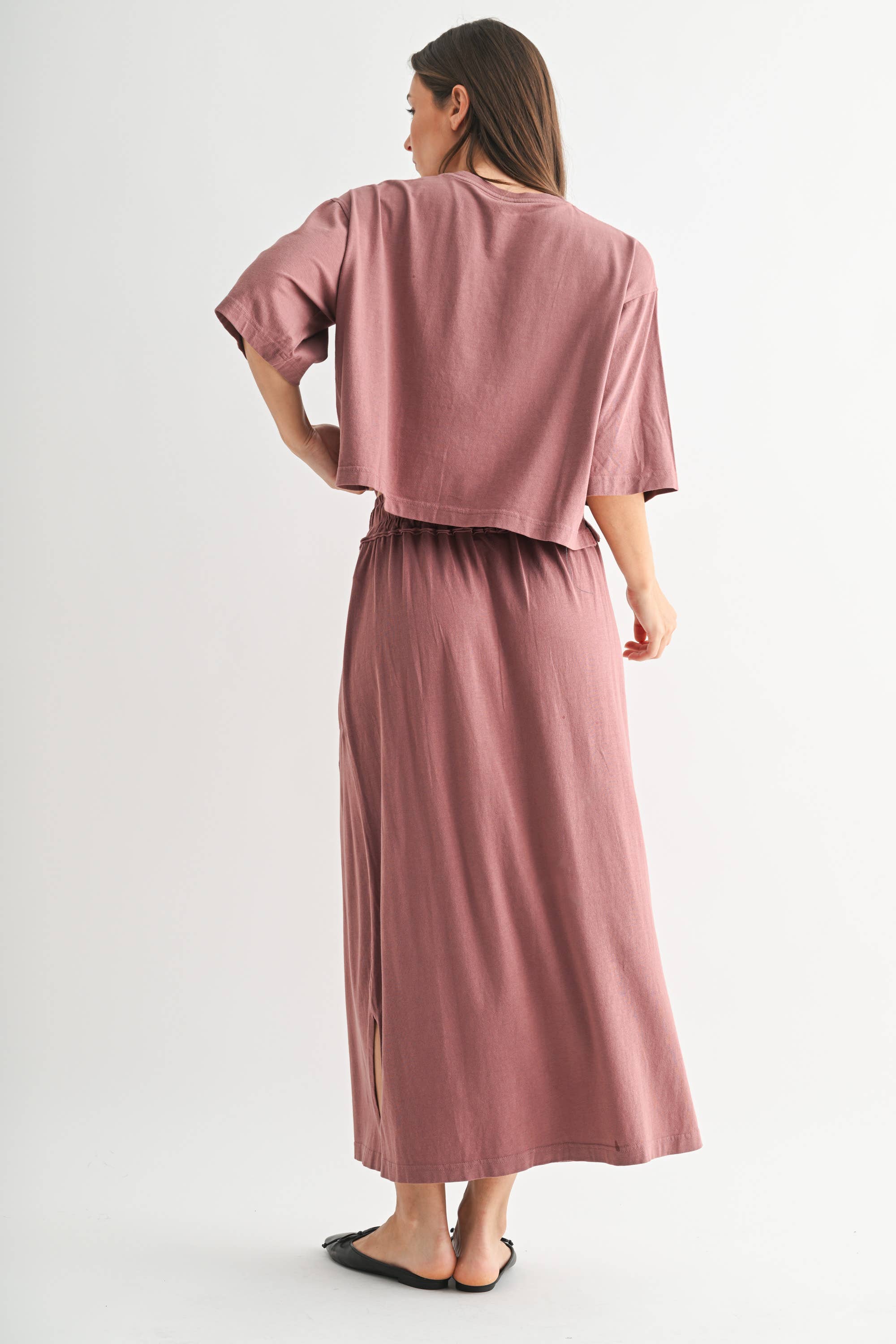 Woman wearing a pink outfit with a long skirt on a white background