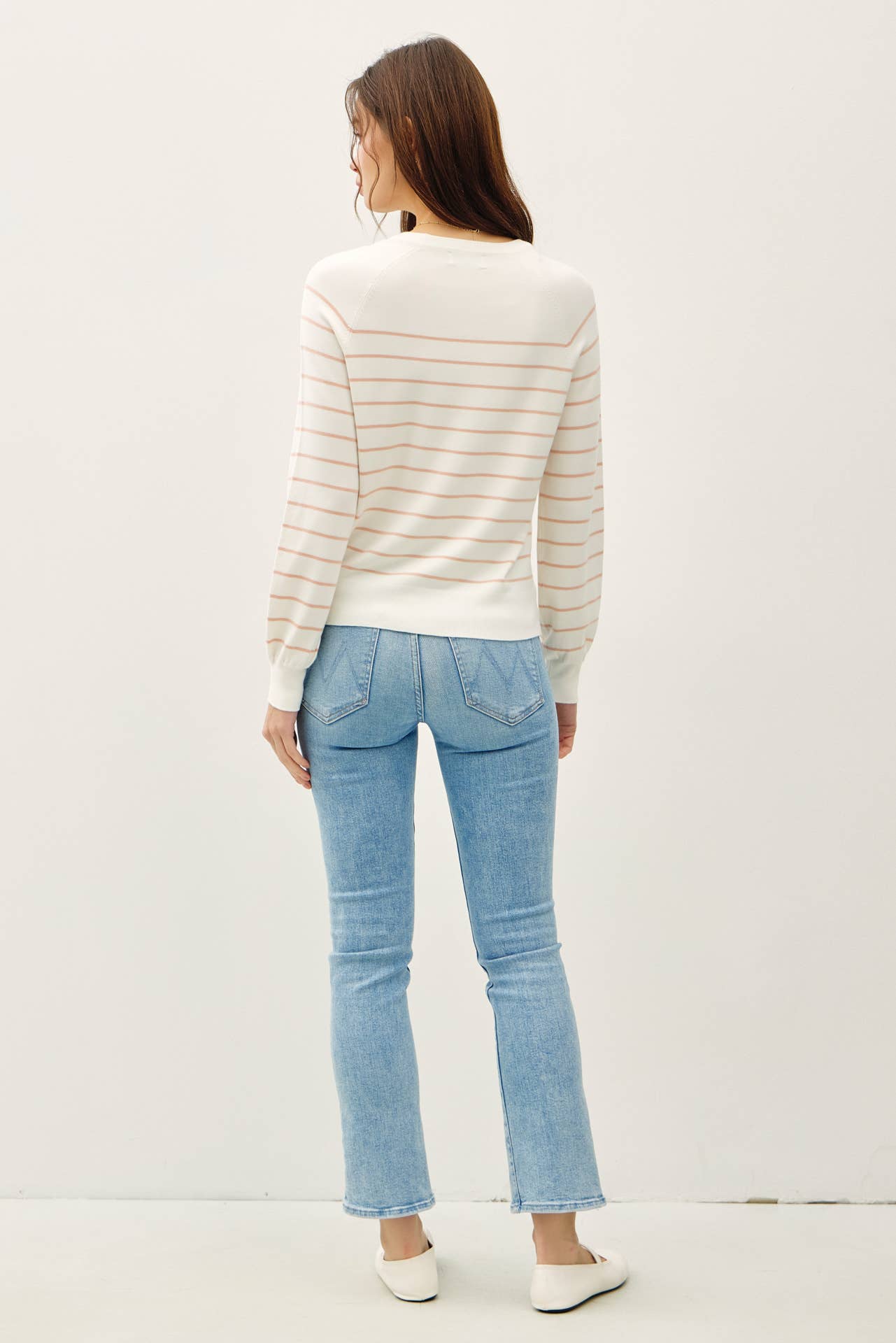 Woman wearing a striped sweater and light blue jeans on a white background