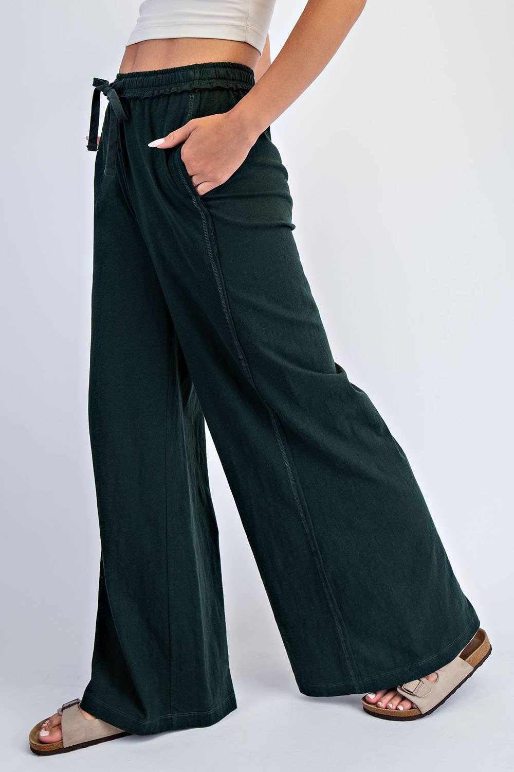 Person wearing dark green wide-leg pants on a white background