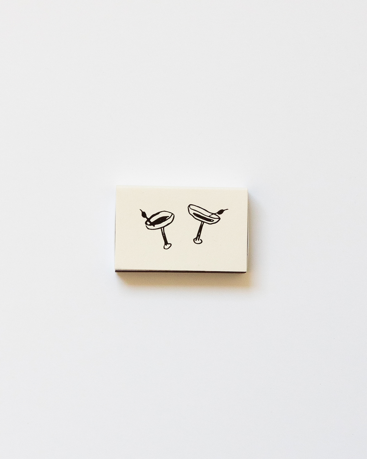 Small beige box with black illustrations of a cocktail glass and a hot dog on a white background