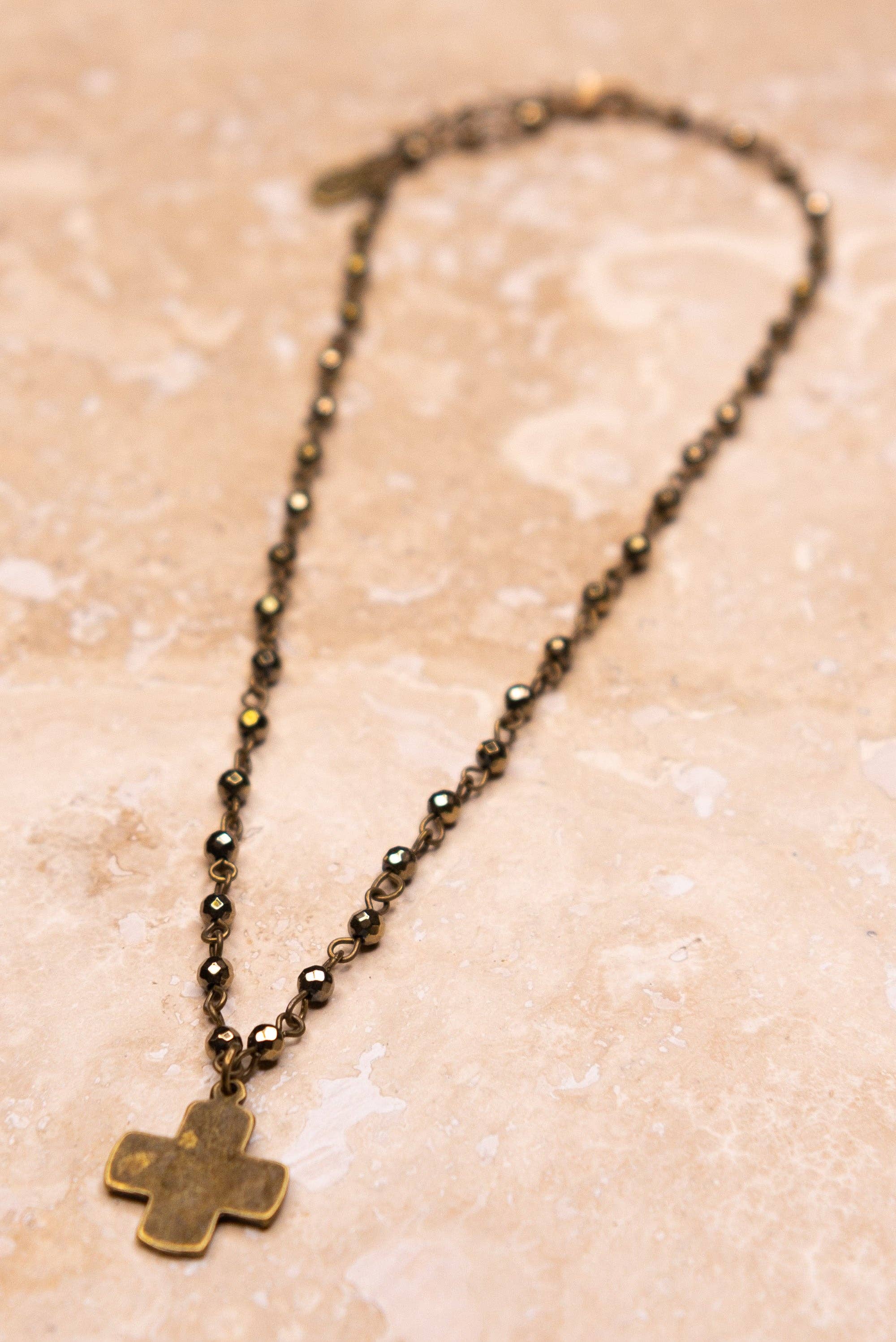Necklace with a cross pendant on a beige textured background
