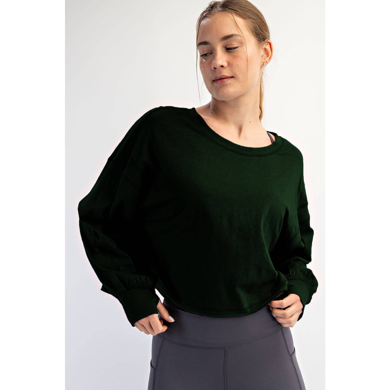 Woman wearing a dark green sweater against a white background