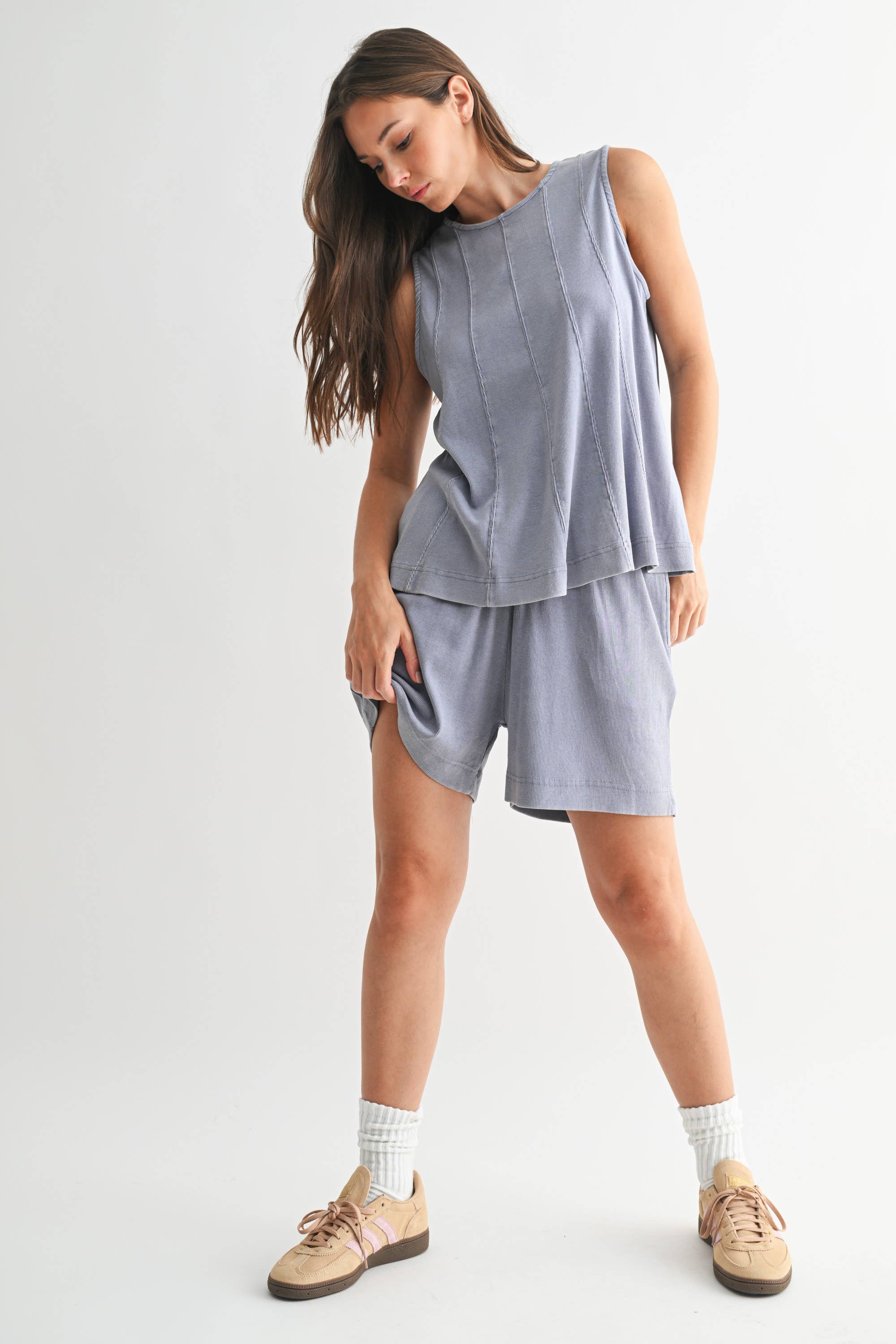 Woman wearing a gray sleeveless top and shorts set on a white background