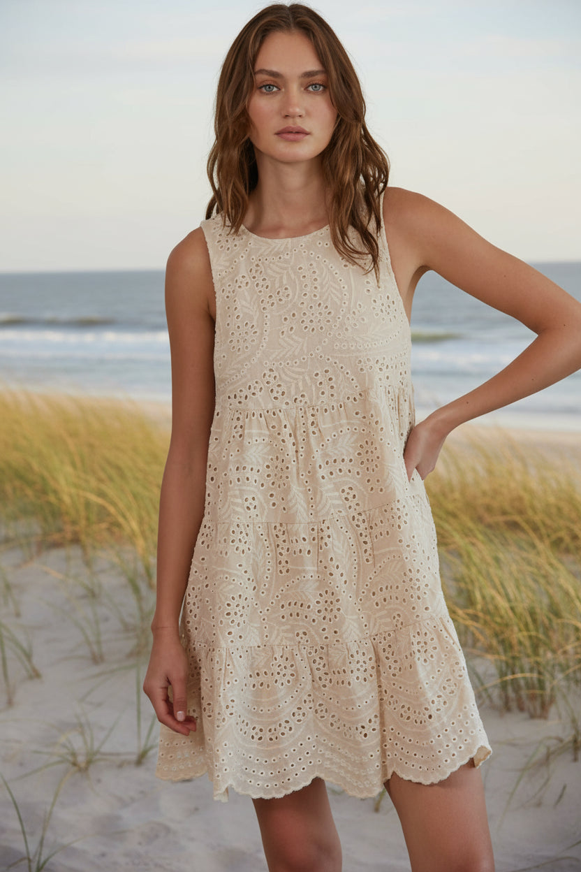 Woman wearing a beige lace dress against a plain background