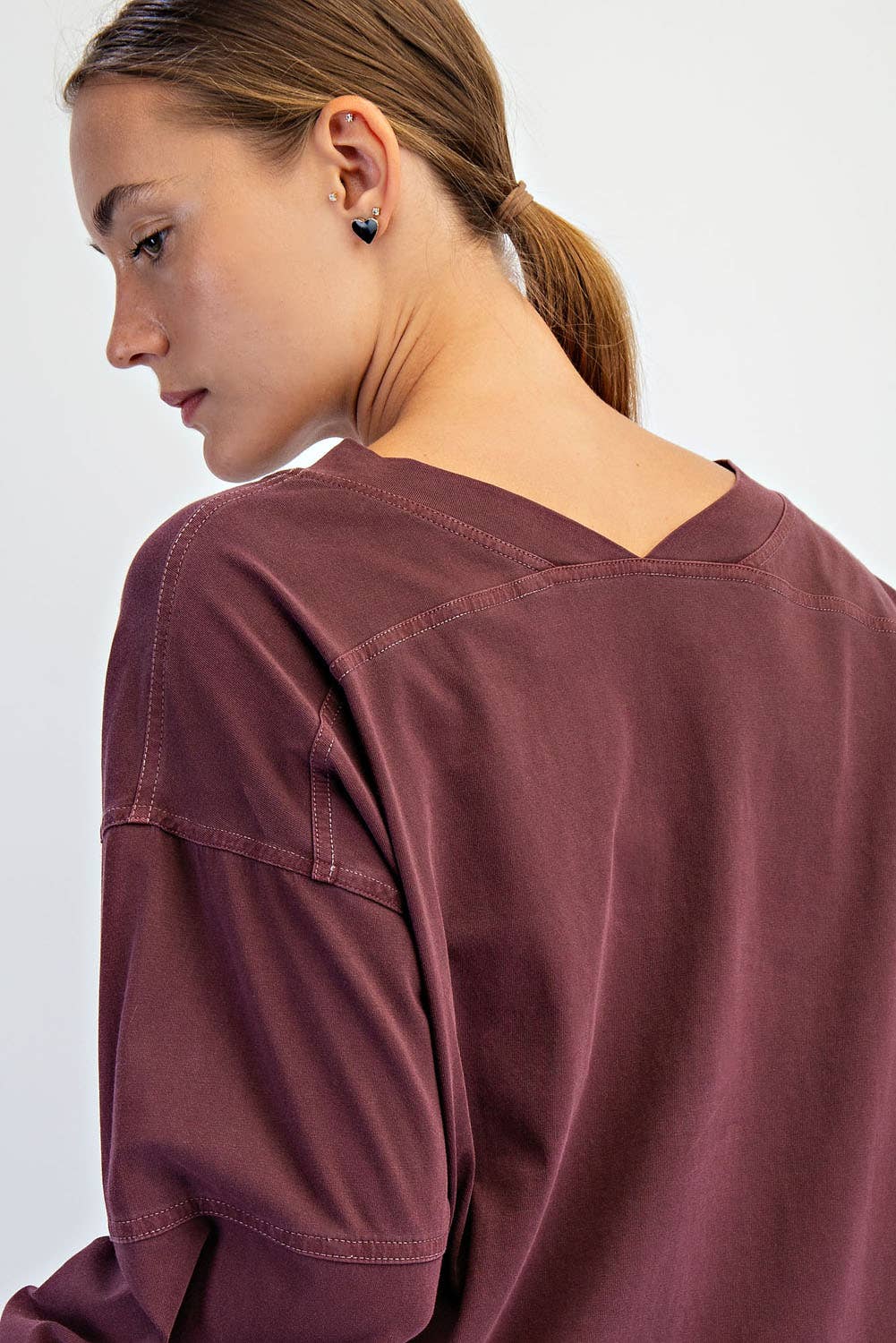 Person wearing a maroon long-sleeve shirt on a white background