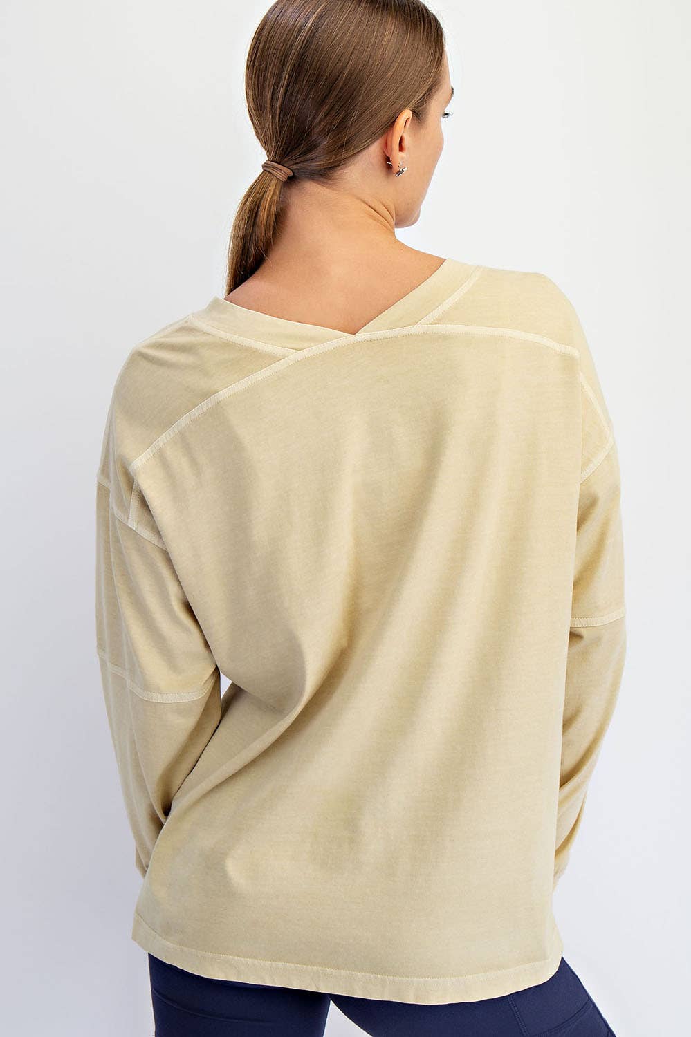 Beige long-sleeve top worn by a person on a white background