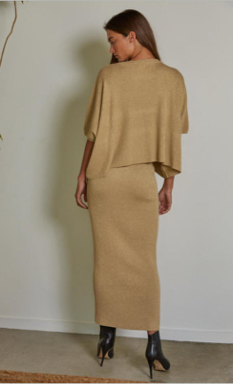 Woman wearing a beige outfit against a plain wall