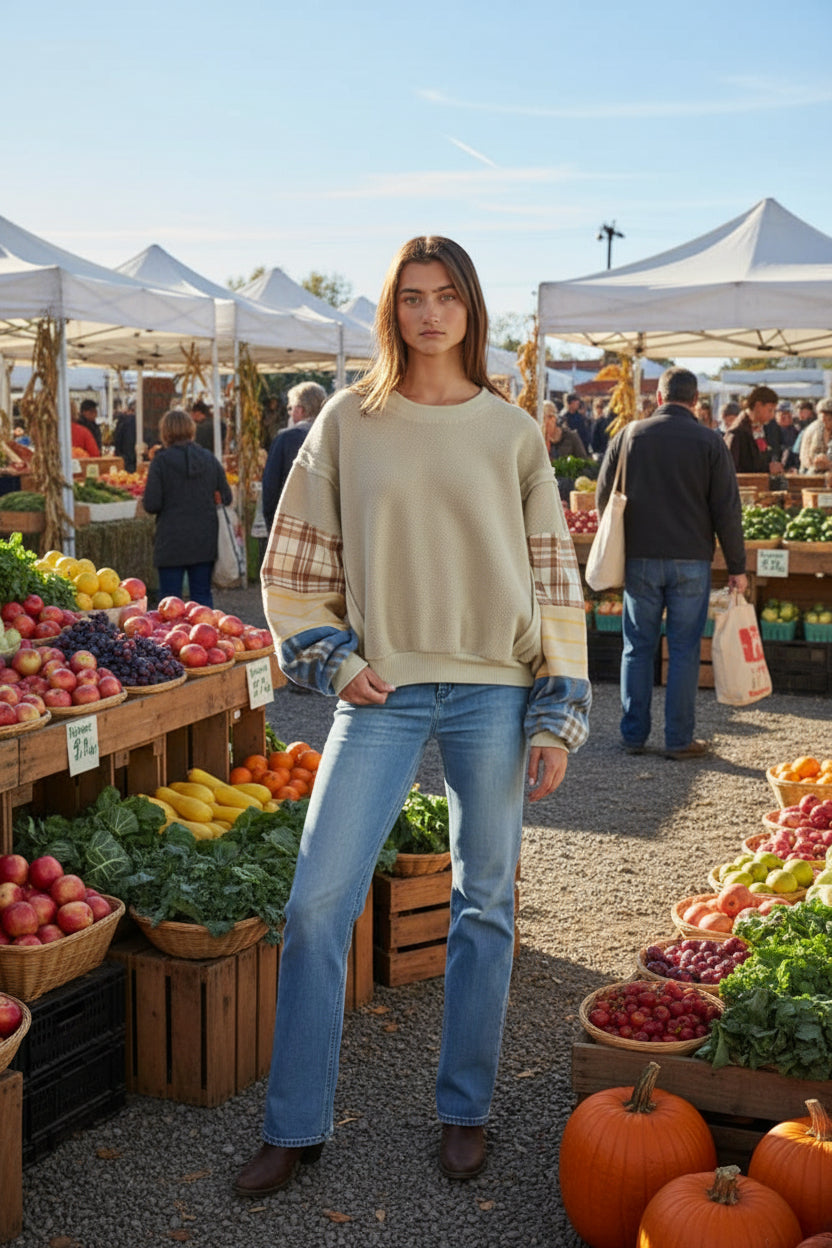 Woman wearing a sweater with plaid sleeves against a neutral background