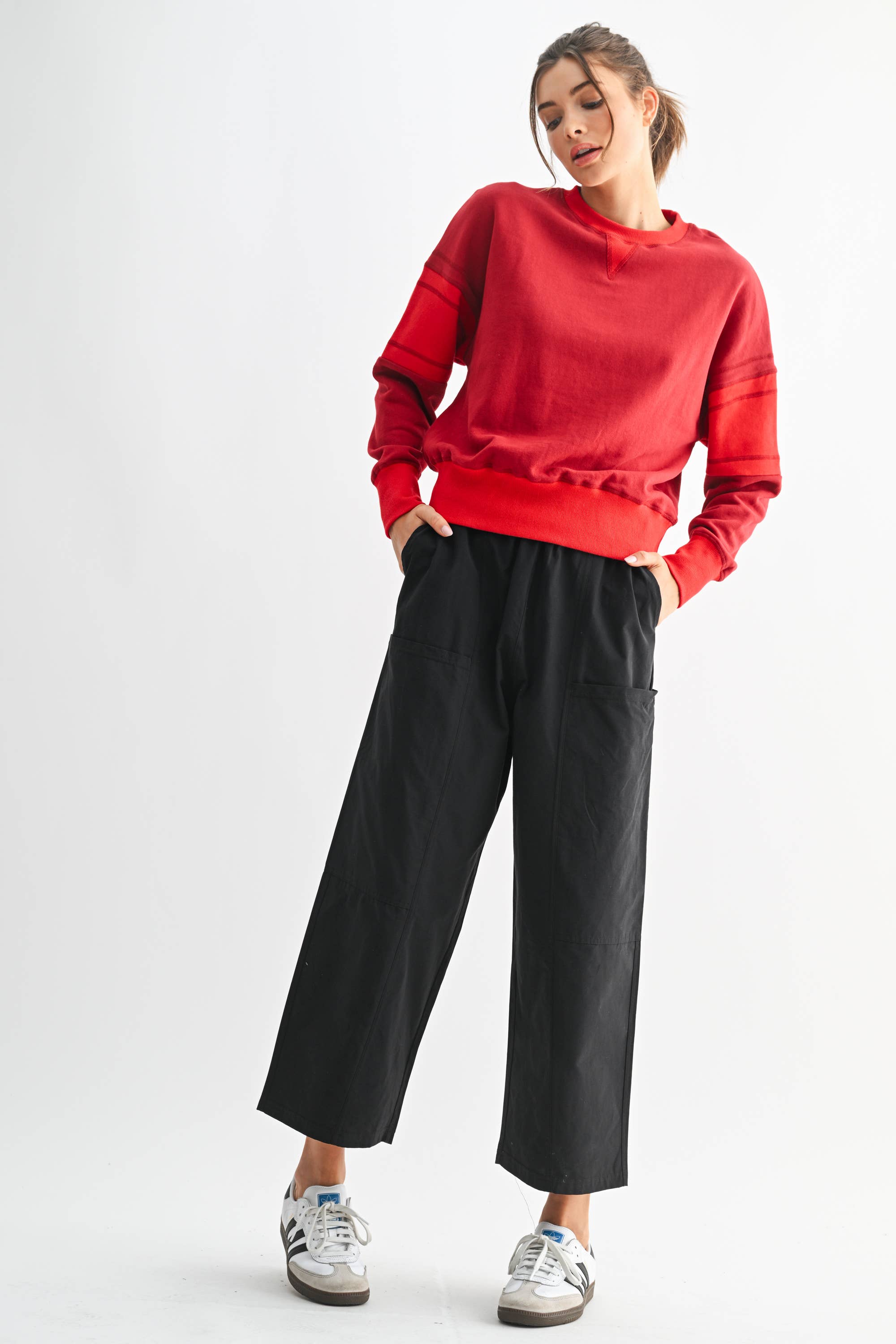 Woman wearing a red sweatshirt and black pants on a white background