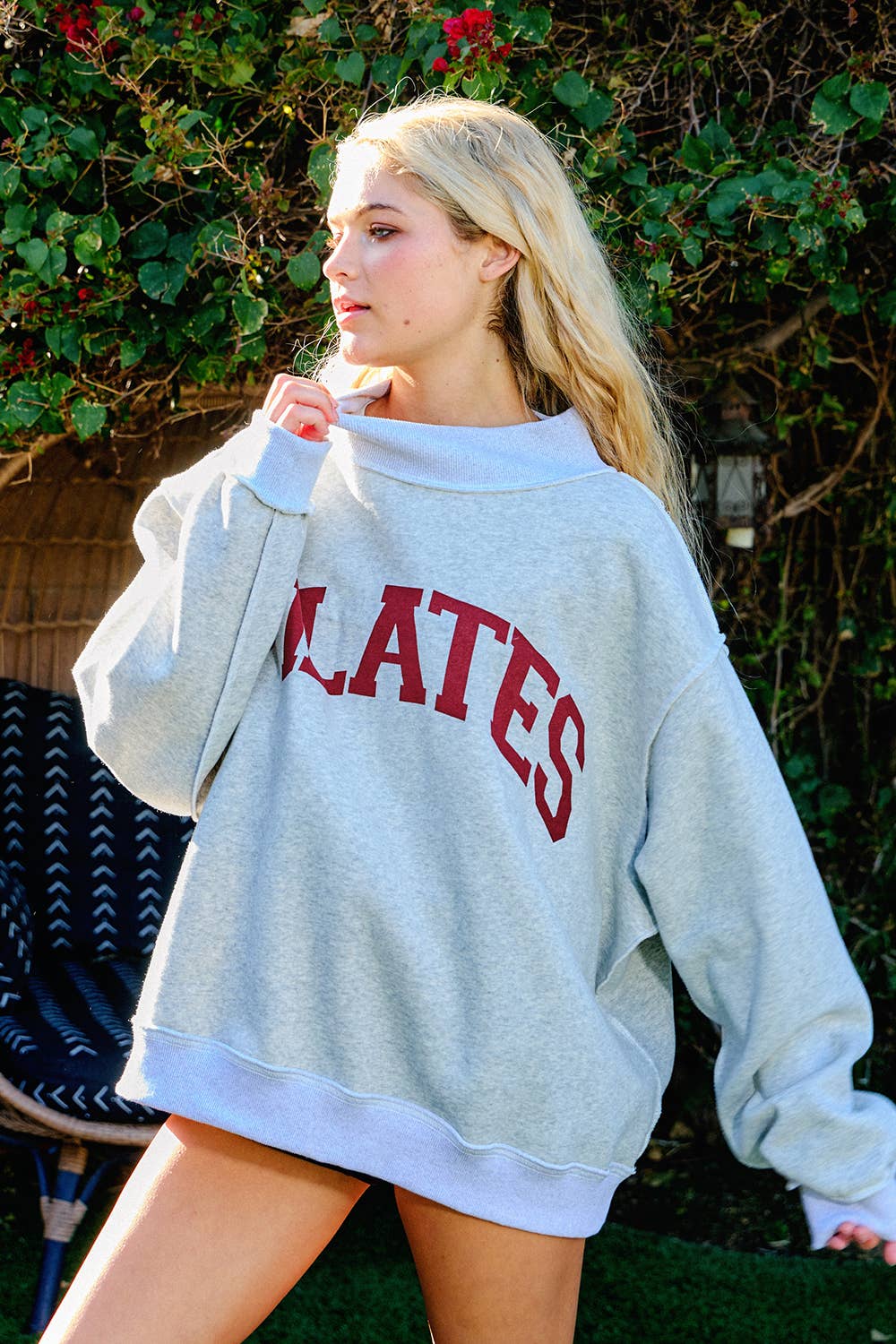 Person wearing a gray sweatshirt with 'CLATES' printed in red letters, standing outdoors.