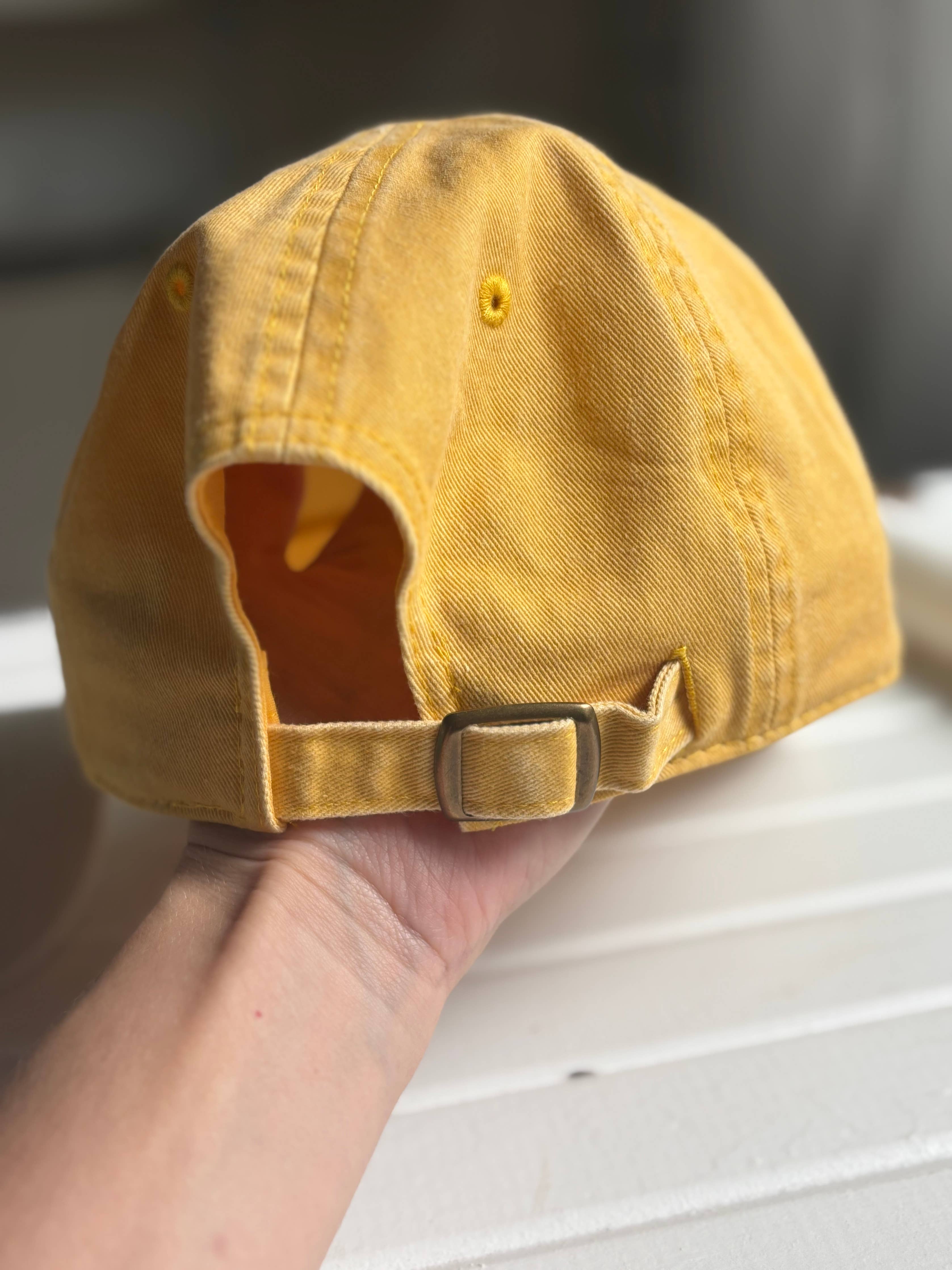 Yellow cap held by a hand on a neutral background