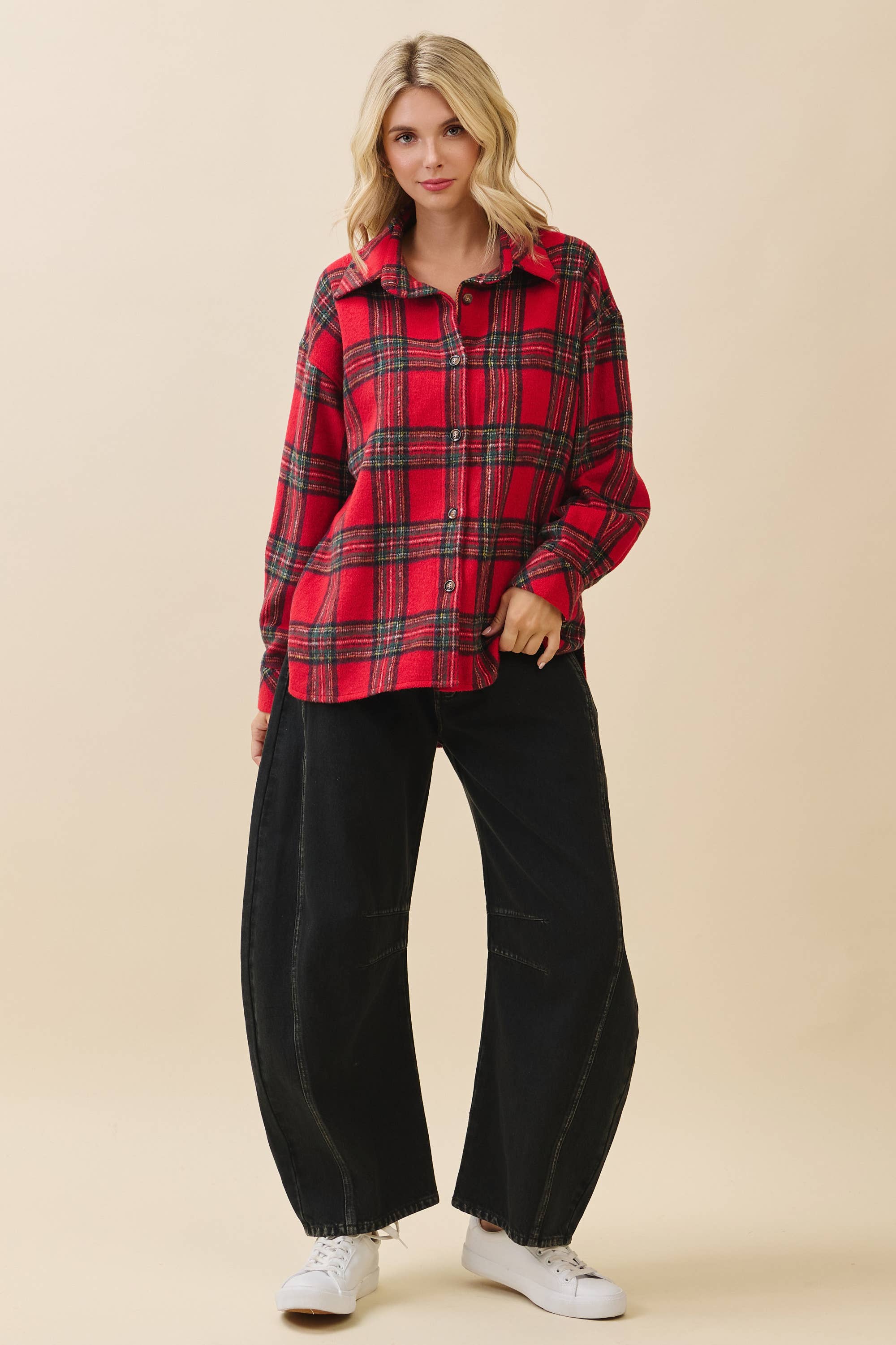 Woman wearing a red plaid shirt and black pants on a beige background