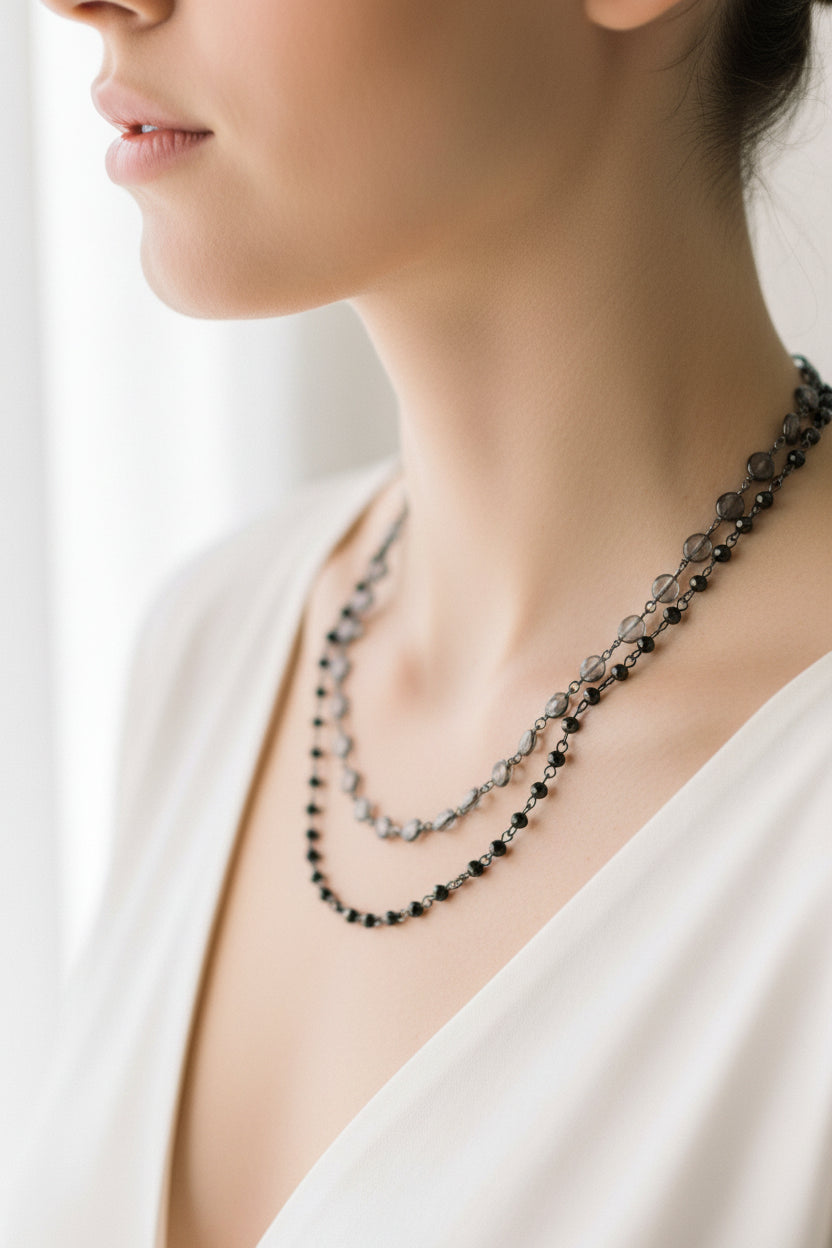 Two black beaded necklaces on a beige surface