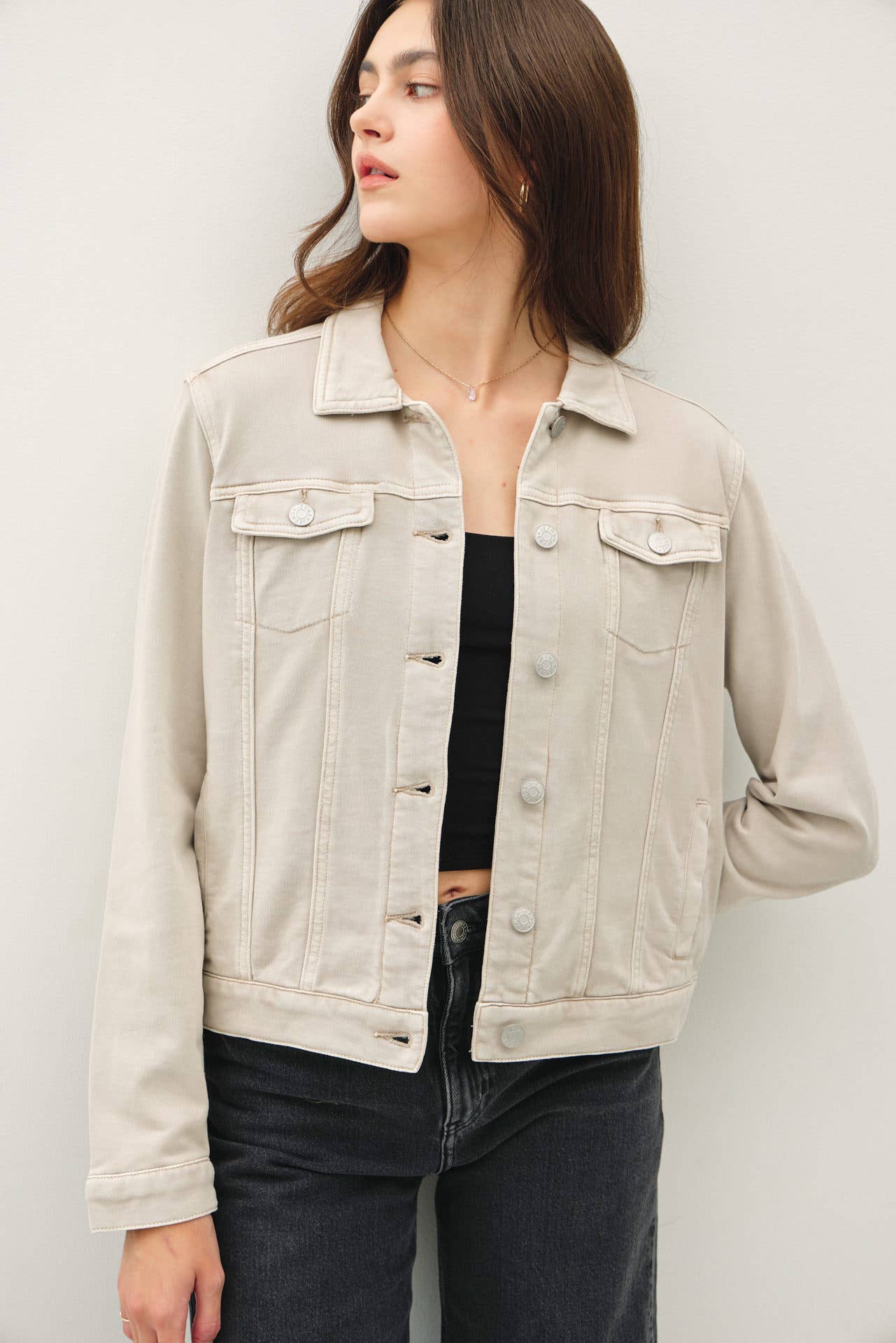 Woman wearing a beige denim jacket against a plain background