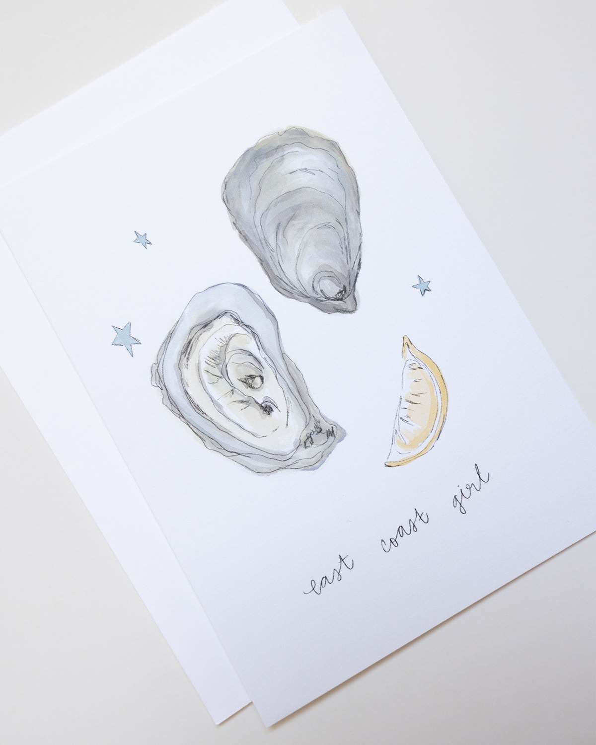Illustration of oysters and a lemon wedge on a card with 'east west girl' text.