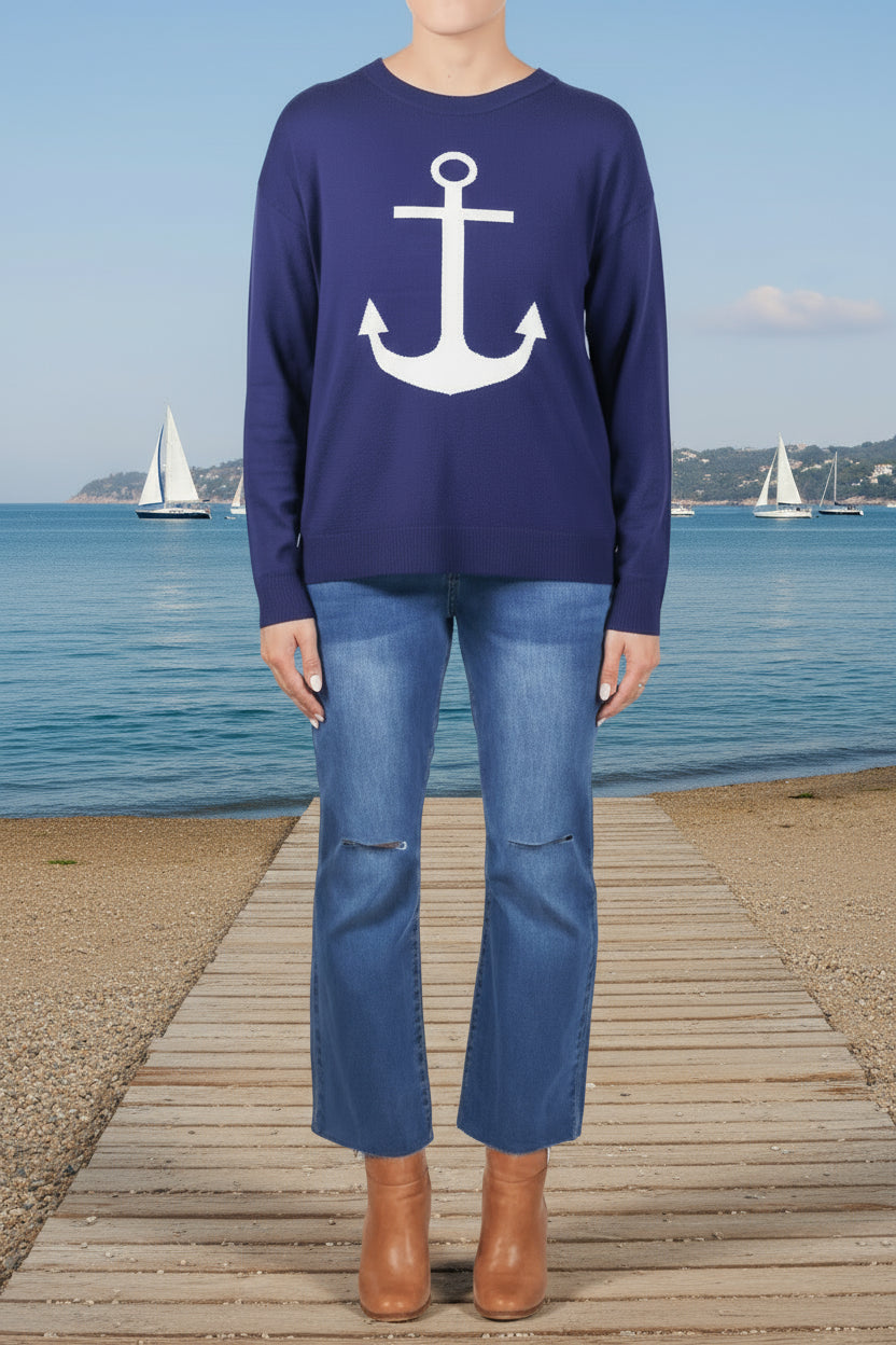 Person wearing a navy blue long-sleeve shirt with a white anchor design and blue jeans on a white background