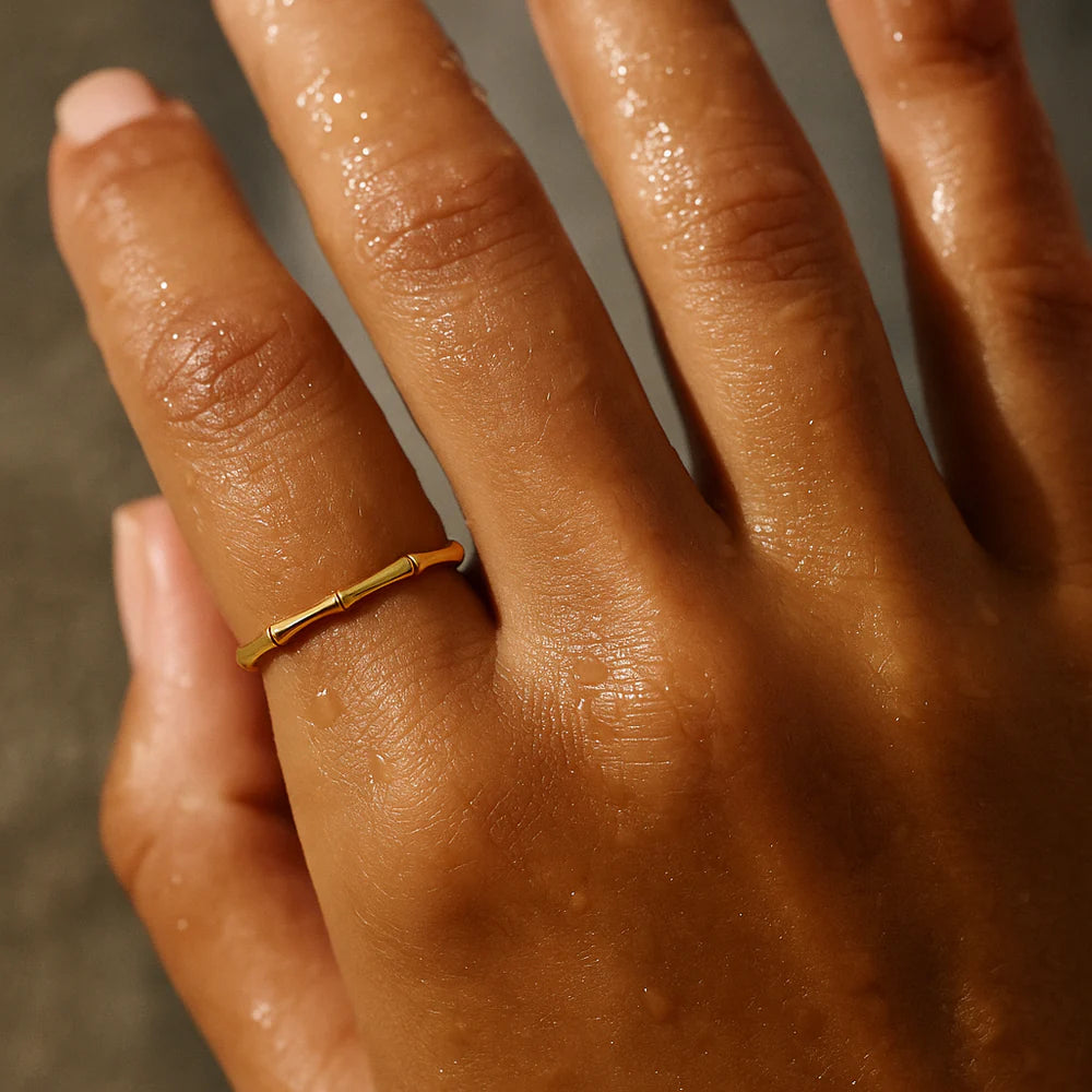 Close-up of a hand wearing a gold ring with a blurred background