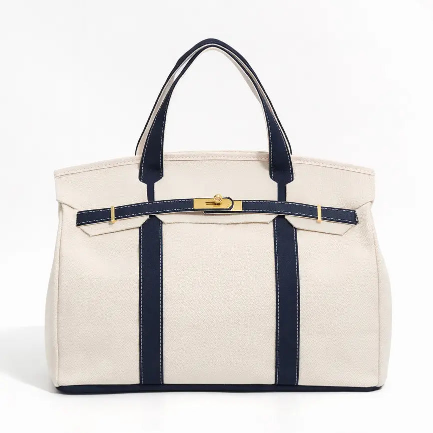 White tote bag with navy accents and gold hardware on a white background