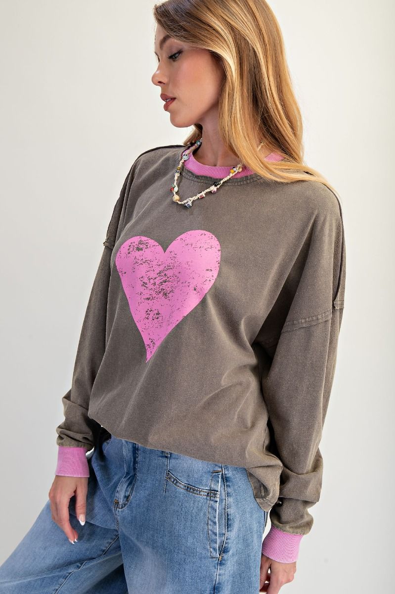 Woman wearing a brown sweatshirt with a pink heart design against a white background