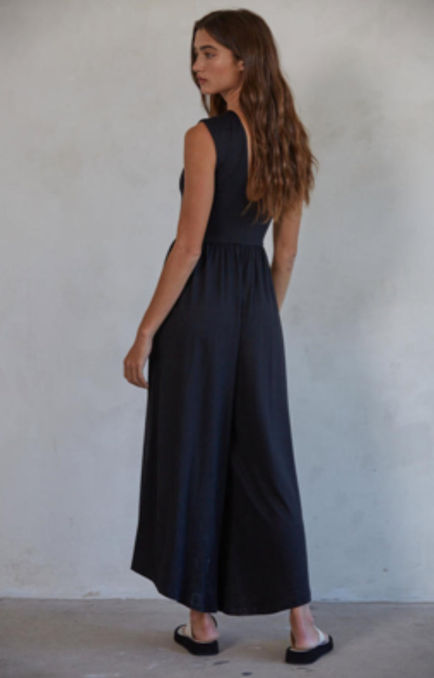 Woman wearing a black sleeveless dress against a plain background