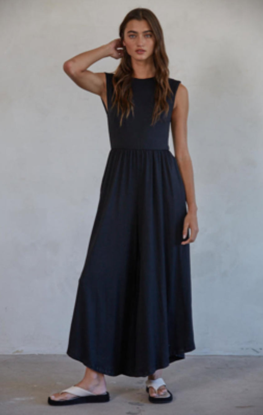 Woman wearing a black sleeveless dress against a plain background