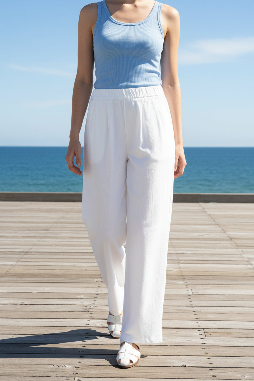Person wearing a navy shirt and white wide-leg pants on a beige background