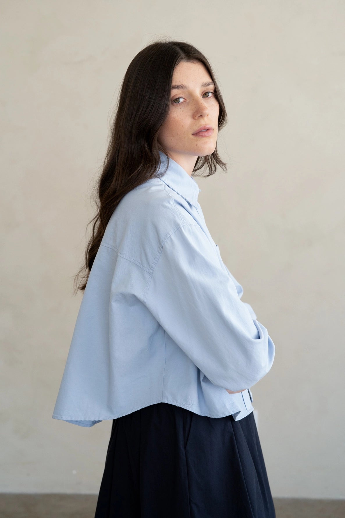 Woman wearing a light blue shirt against a beige background
